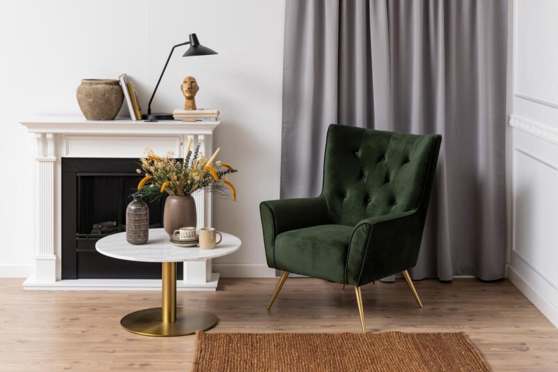 Couchtisch Corby, perspektivisch aufgenommen mit Blick auf ein stilvolles Wohnzimmer mit Samt-Sessel, Kamin und Marmortischplatte.
