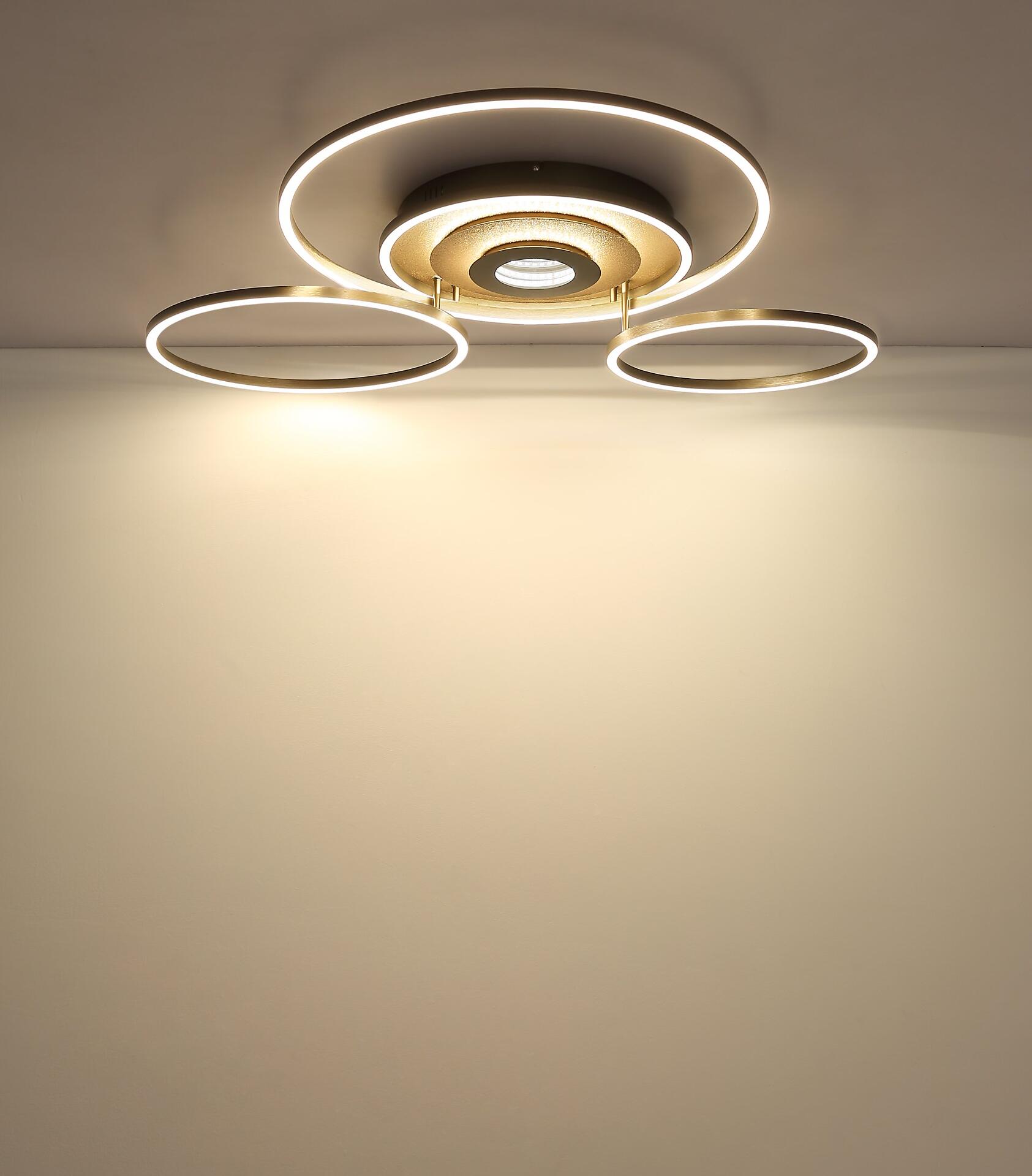 Deckenleuchte MILES mit goldfarbener Metallbasis, drei Ringelementen mit LED-Leuchten und dimmbarer, warmweißer Beleuchtung.