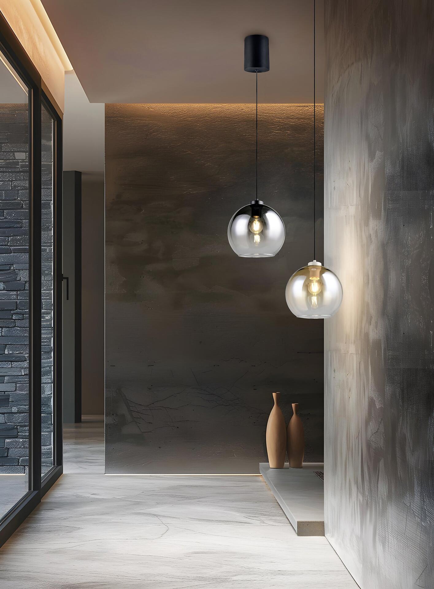 Pendelleuchte Liora mit drei transparenten Glaskugeln unterschiedlicher Höhe, die an einem schwarzen Kabel hängen und warmes Licht abstrahlen.