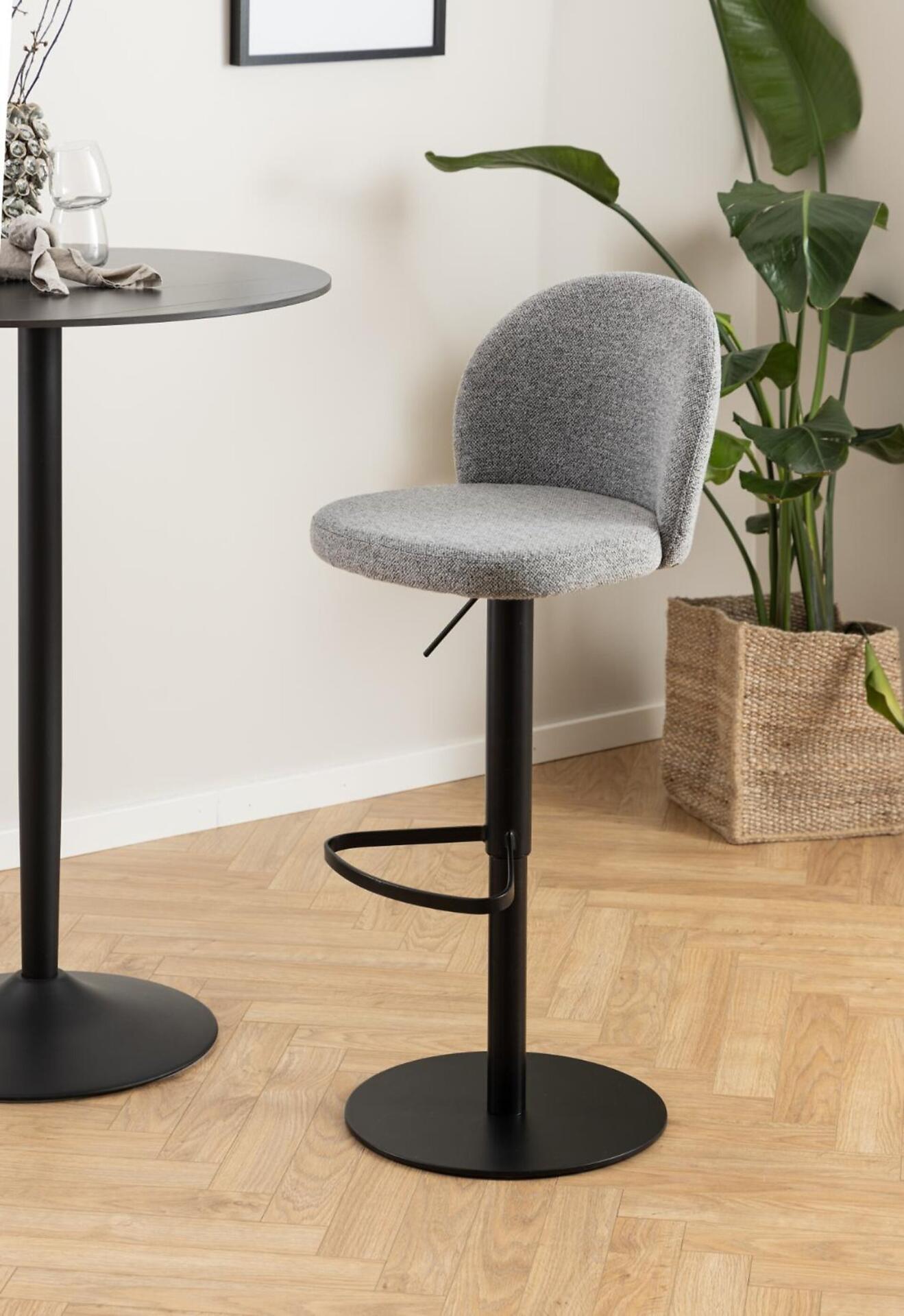 Barhocker Patricia mit abgerundeter Sitzfläche, Fußring und schwarzem Metallfuß, frontal und leicht erhöht fotografiert.
