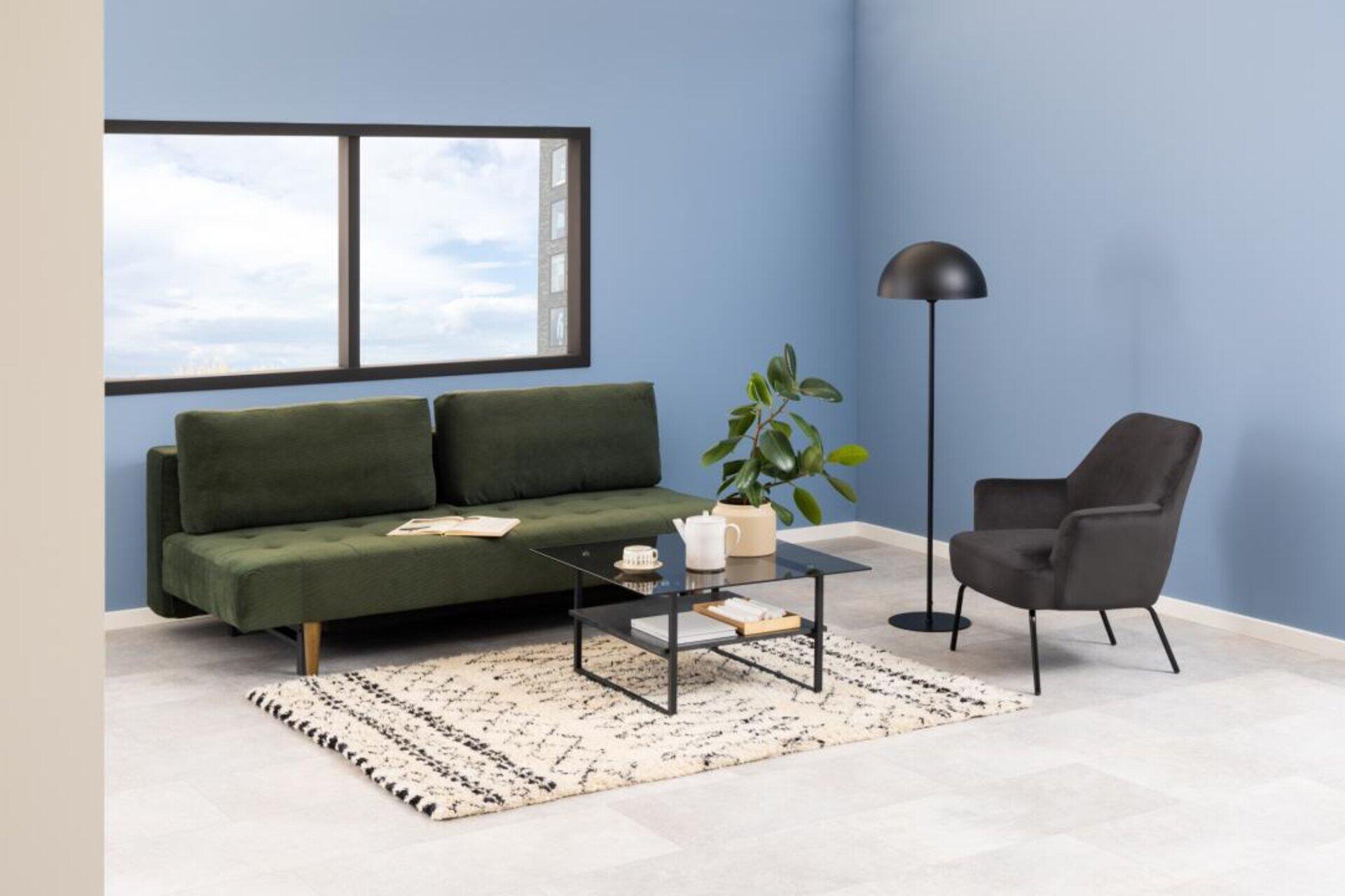 Melissa Loungestuhl in Schwarz, seitlich im Raum vor einem Sofa platziert, mit Beistelltisch und Teekanne.