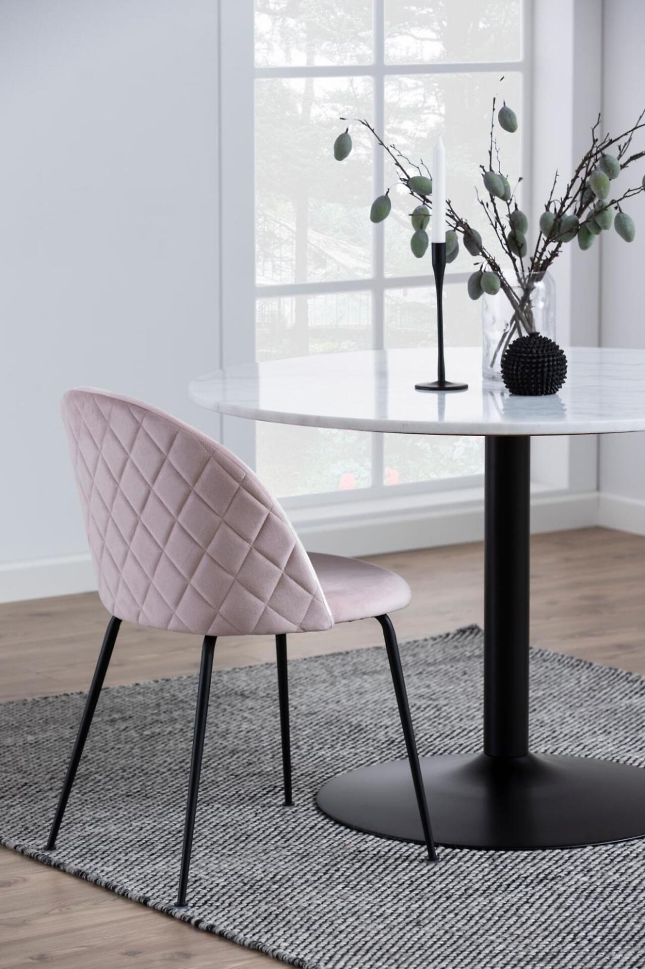 Esszimmerstuhl mit gepolsterter, rosa-farbener Rücklehne und schwarzen Metallbeinen am runden, marmorierten Esstisch Tarifa.