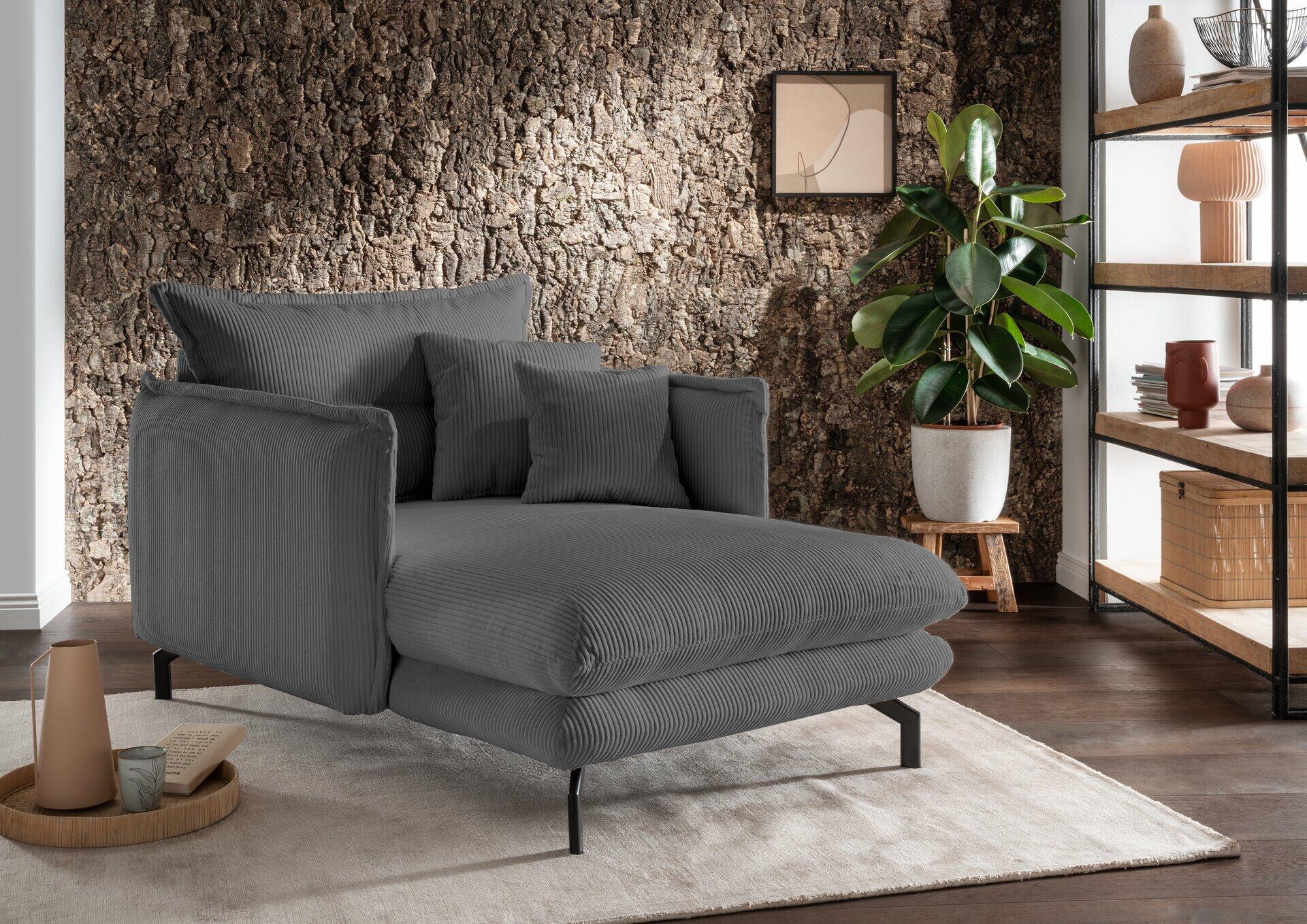 Grauer Loveseat Lava mit schwarzem Metall-Winkelfuß, aus leicht seitlicher Perspektive, zeigt die gepolsterte Sitzfläche und hohe Rückenlehne für bequemes Entspannen.