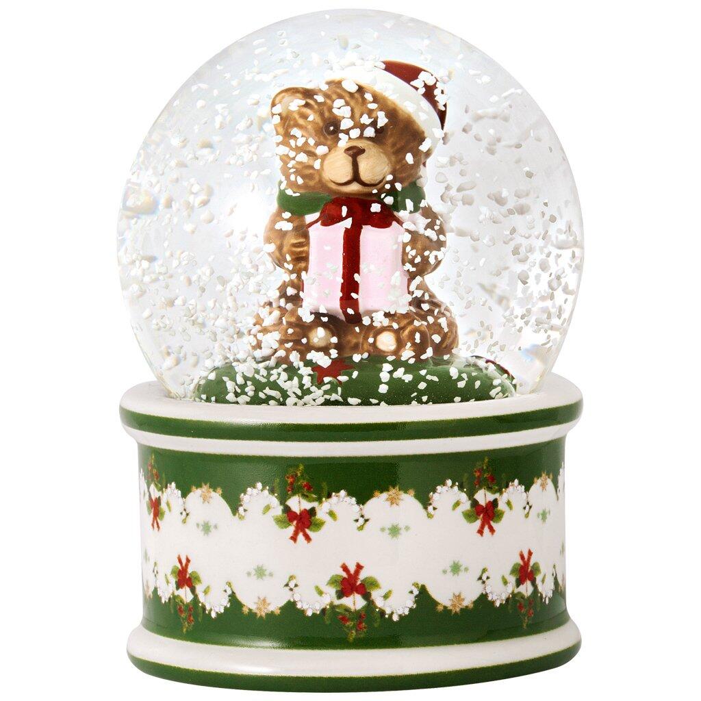 Schneekugel mit Bär, der ein Geschenk hält, auf grünem Sockel mit weihnachtlichen Verzierungen.