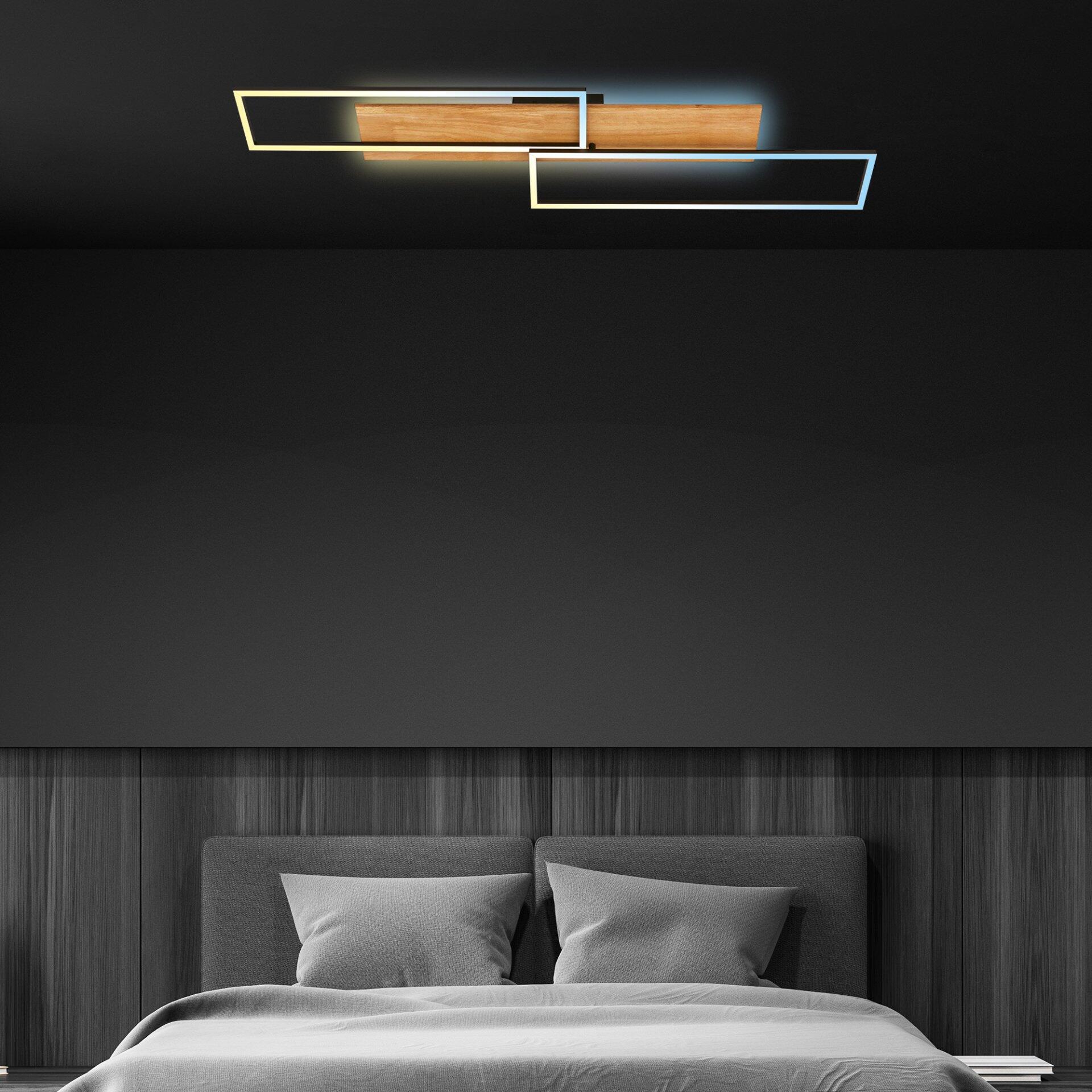 Moderne Wandleuchte Cornice mit zwei geometrischen Elementen, Holzfurnier und indirekter Beleuchtung, montiert an einer Wand mit Holzstruktur über einem Bett.