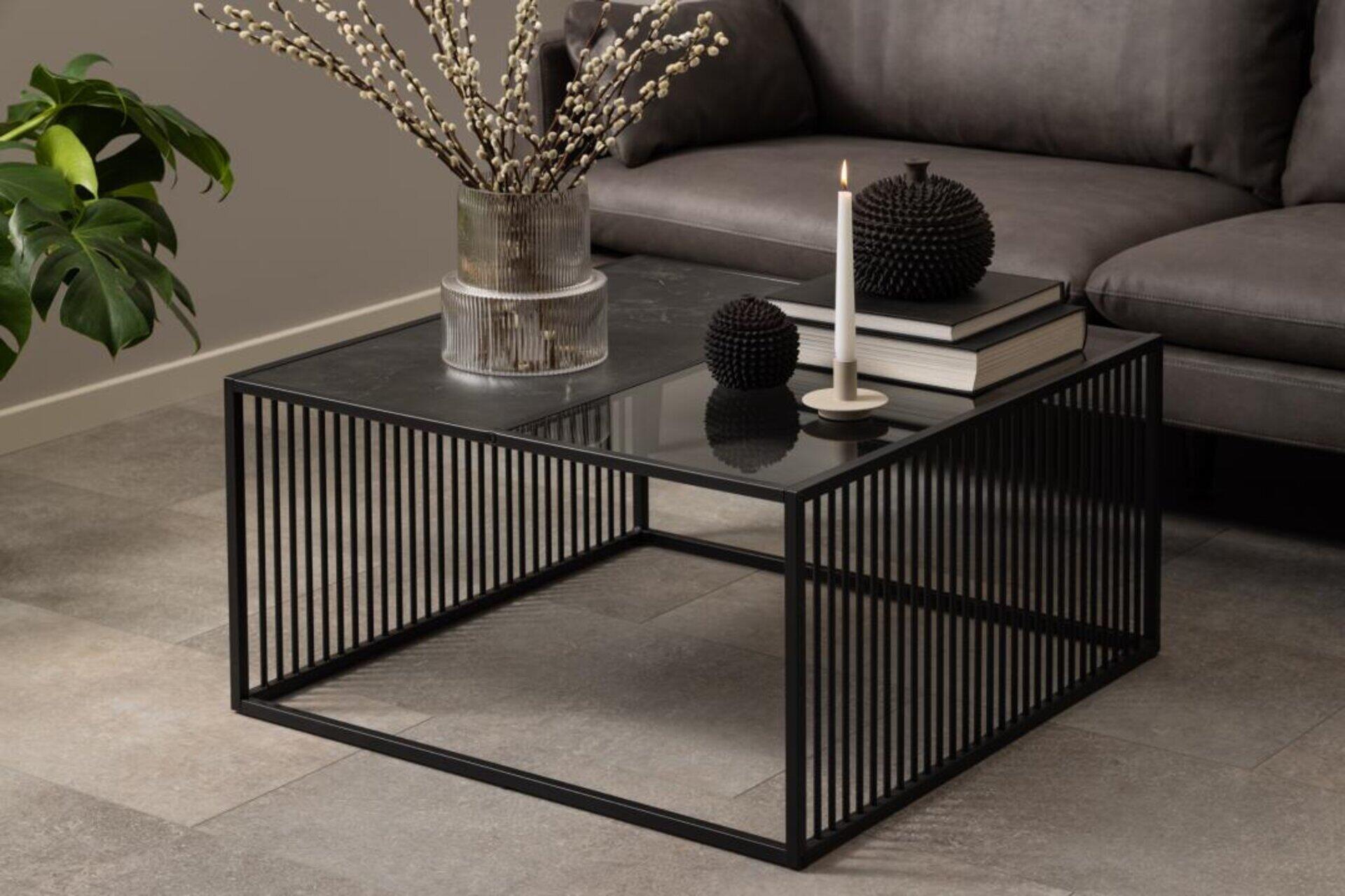 Couchtisch Strington mit rechteckiger Glasplatte, schwarzem Metallrahmen aus parallelen Stäben und integrierter Ablagefläche.