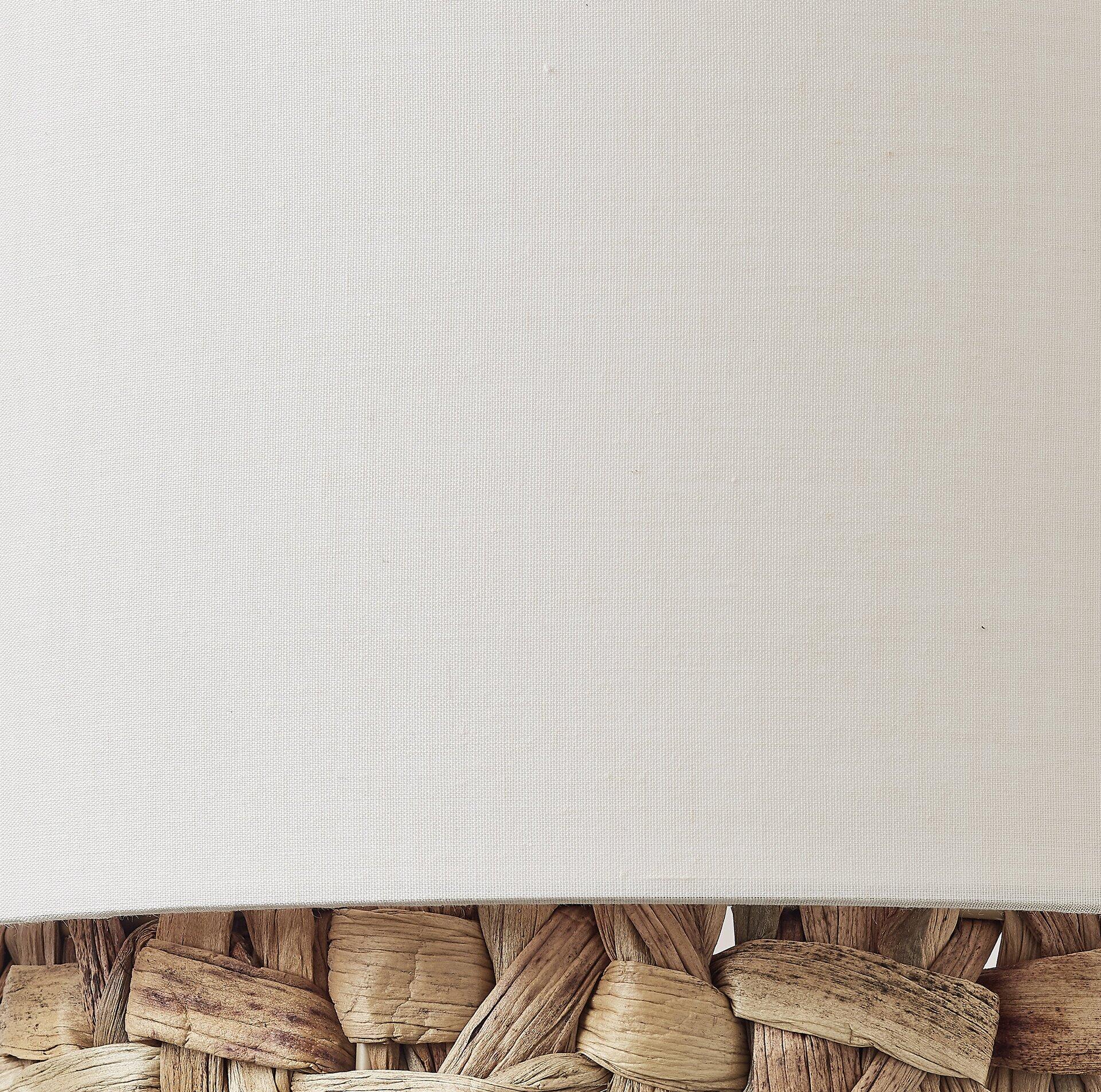 Detailaufnahme des Rattan-Körbchens der Stehleuchte Waterlilly mit beigem Stoffeinsatz.
