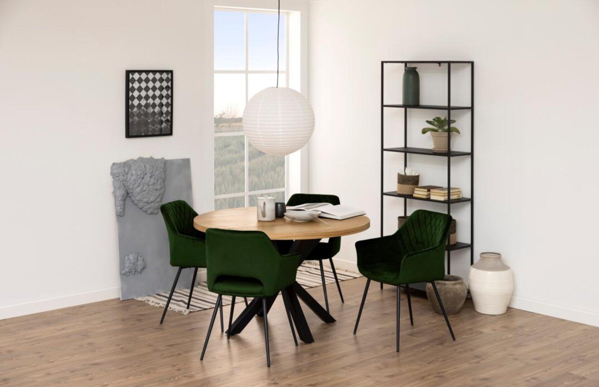 Regal Newcastle mit offenen Böden, einer Pflanze, Büchern und dekorativen Elementen, dargestellt in einem hellen Essbereich mit rundem Holztisch und Samtstühlen.
