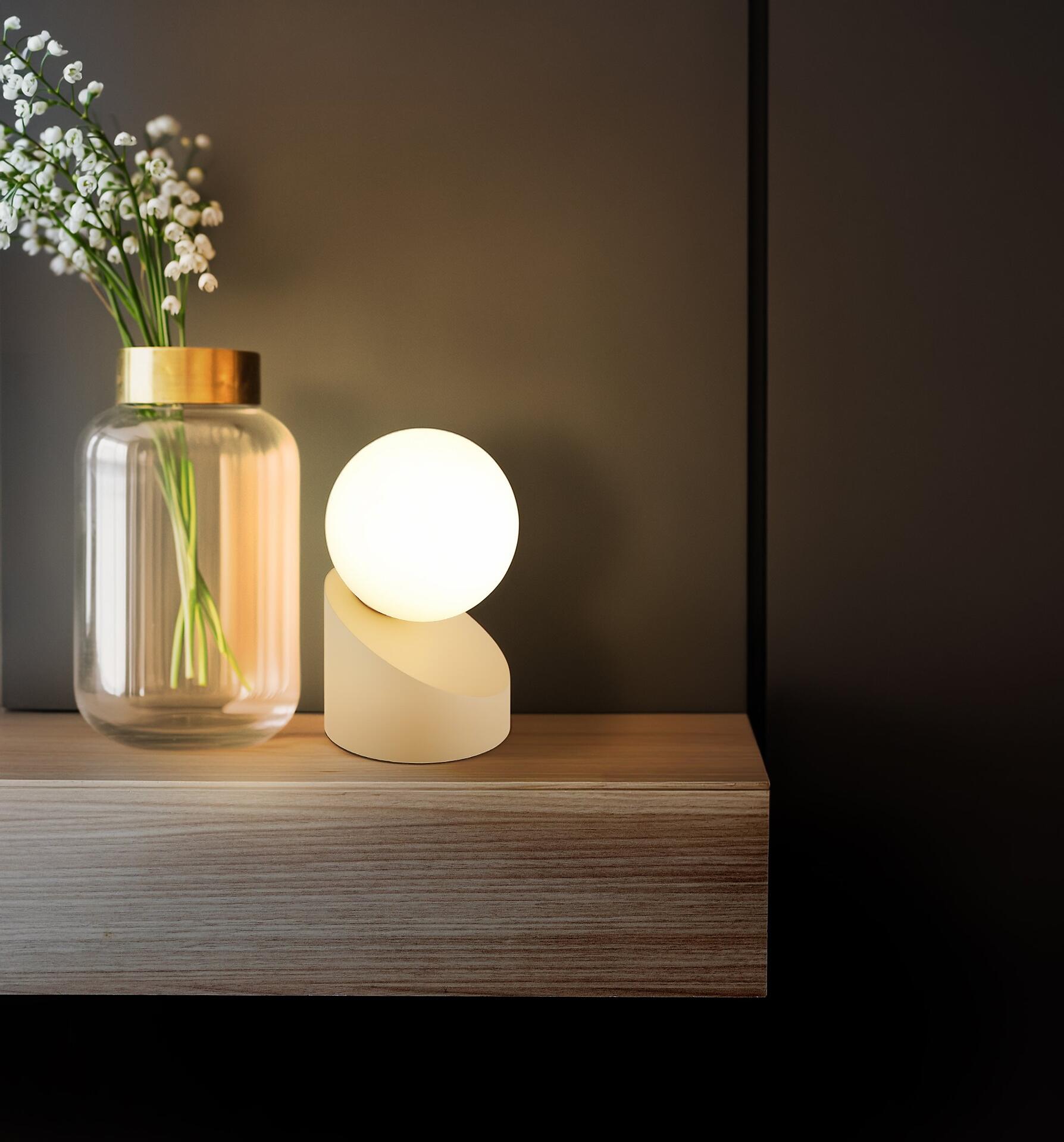 Tischleuchte ALISA mit runder Glaskugel und Touch-Funktion, beleuchtet eine Holzablage.
