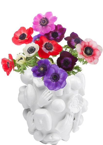 Weiße, handgefertigte Vase im skulpturalen Design mit reliefartigen Darstellungen menschlicher Körperteile, bepflanzt mit bunten Anemonen.