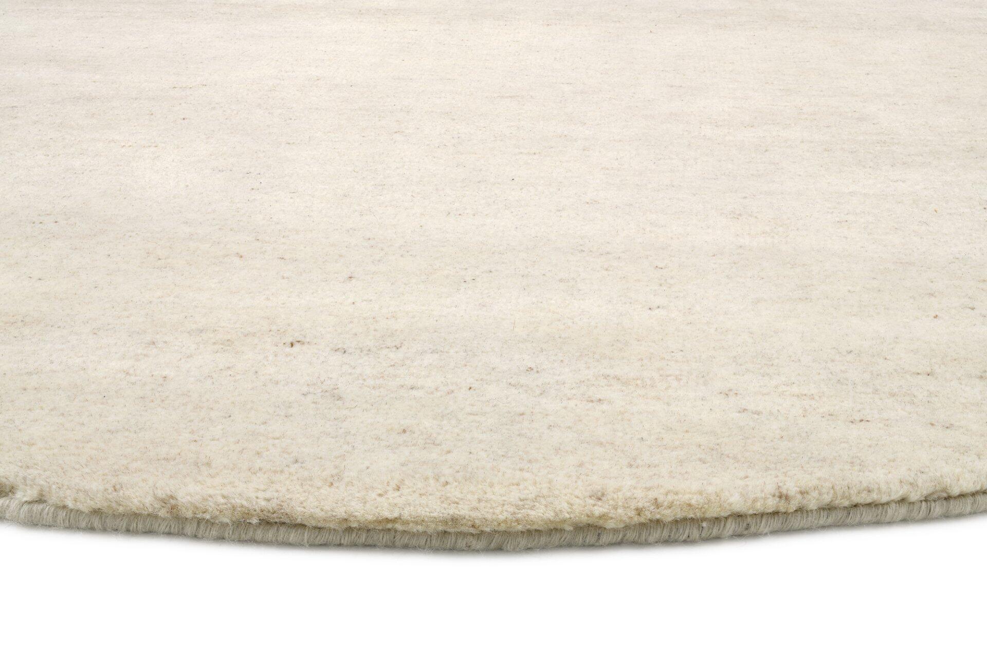 Nahaufnahme des handknüpfte Teppichs Assos mit cremefarbenem Flor und strukturierter, hellbeige Randbordüre auf weißem Hintergrund.