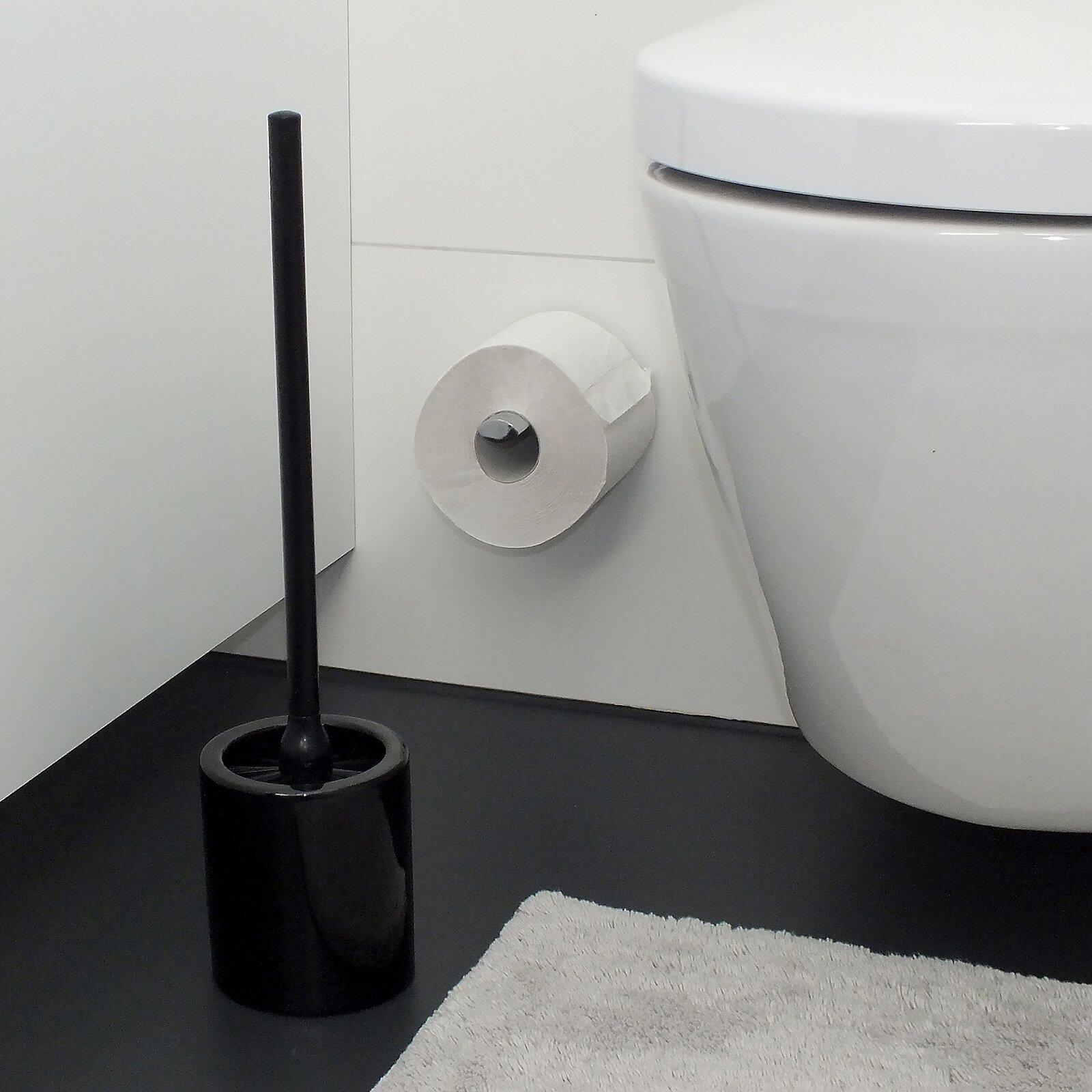 Toilettenbürste Mono mit schwarzem Griff und Bürstenkopf auf schwarzem Boden, vor einem weißen WC.