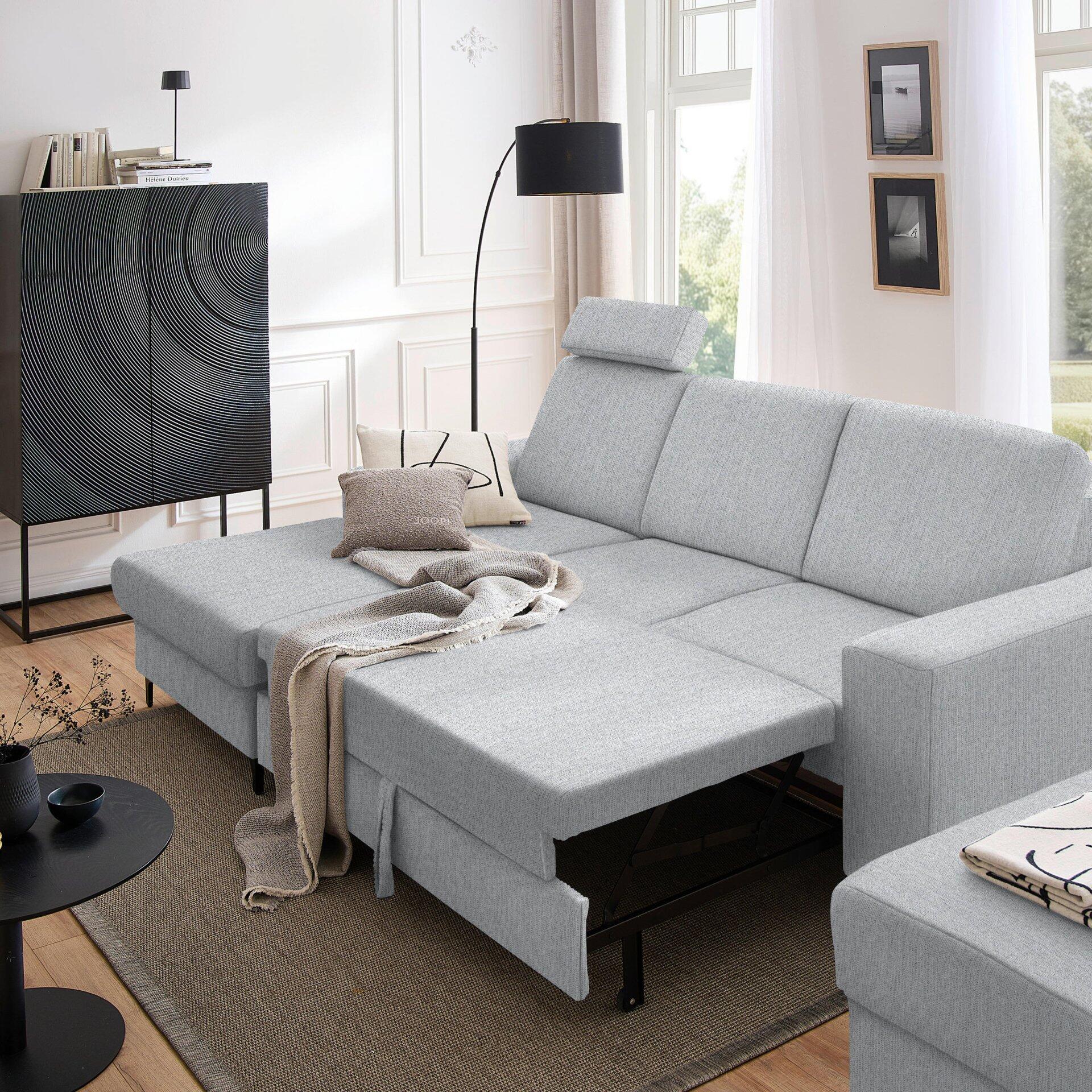 Graues Ecksofa Balina mit ausgezogener Schlaffunktion und Lattenrost, dargestellt in U-Form aus leicht seitlicher Perspektive in einem modernen Wohnzimmer.