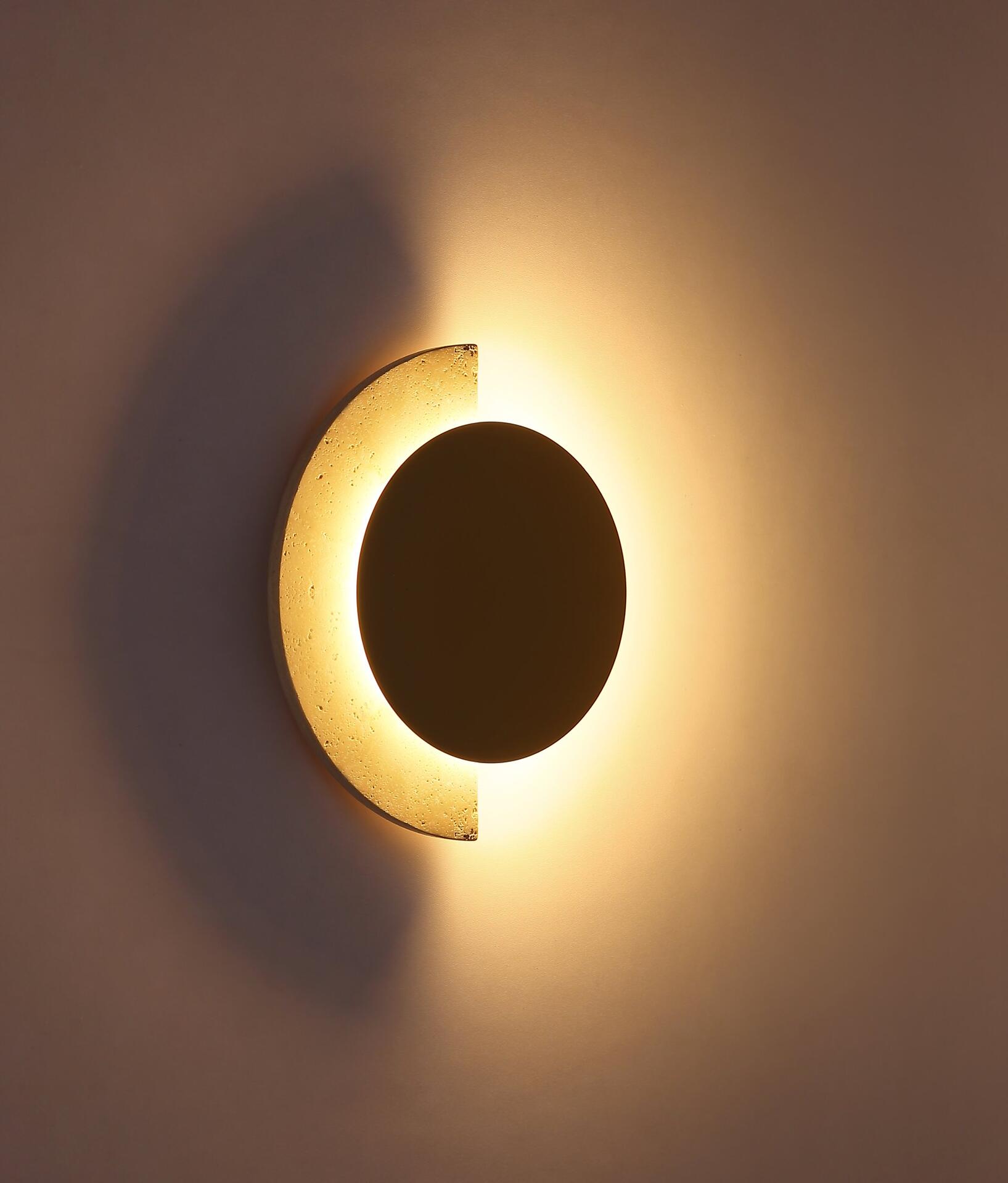 Wandleuchte ROJAS mit Mondsichel-Design und warmweißem LED-Licht, zeigt eine frontale Ansicht des kreisförmigen Kerns mit abgebrochenem Rand, der einen Lichtschein auf die Wand wirft.