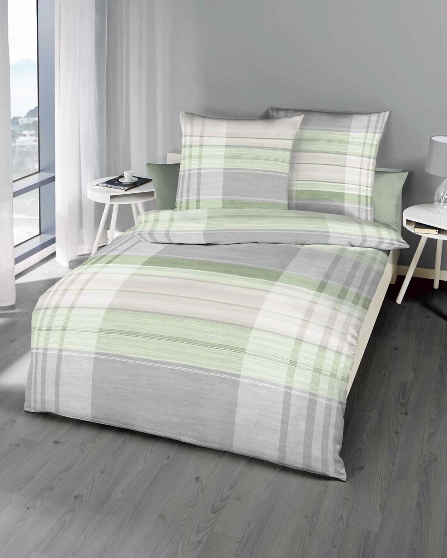 Bettwäsche Brush im Karomuster mit Kissen auf einem Bett in einem hellen Schlafzimmer, Detailaufnahme von Bett und Beistelltisch.