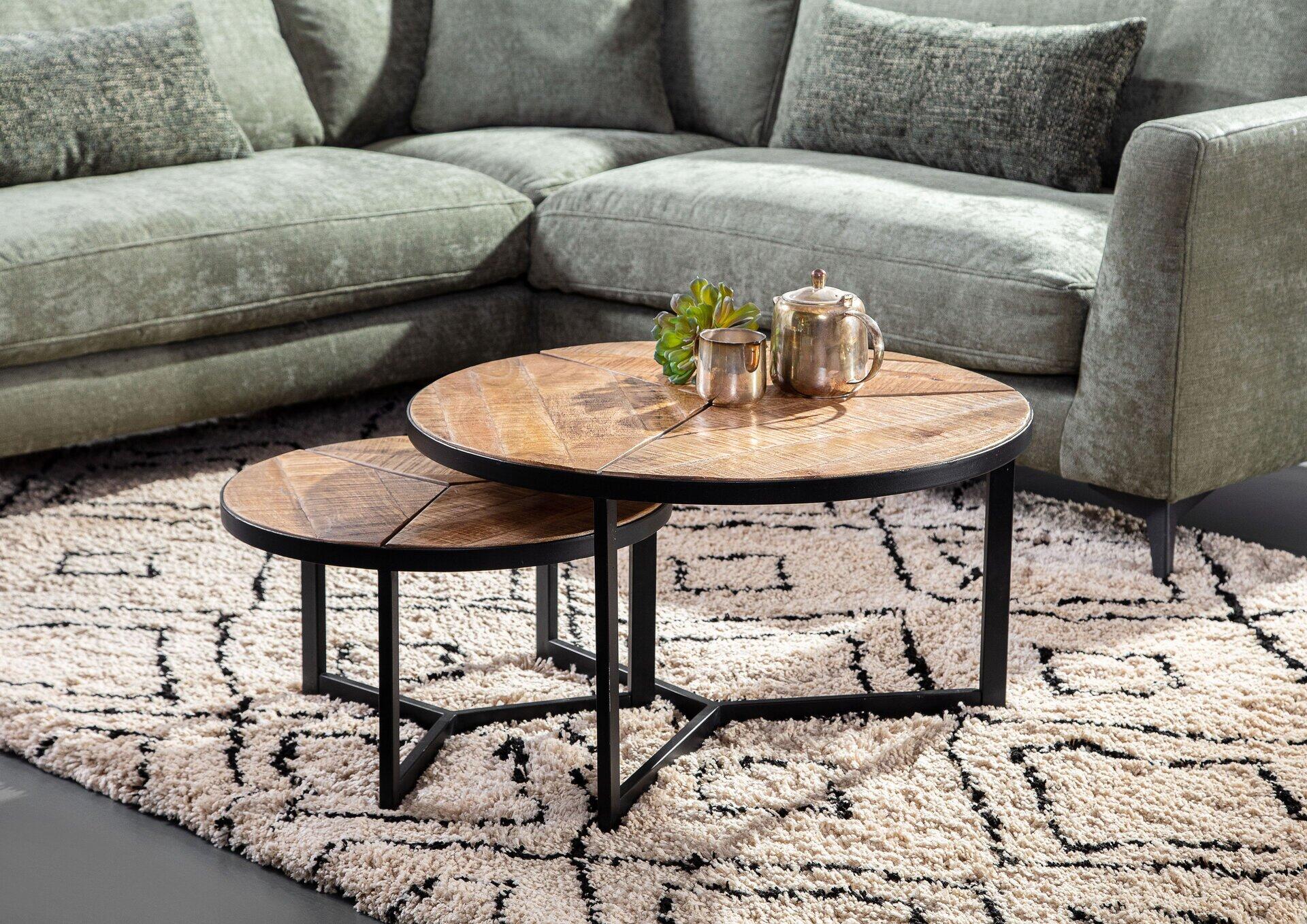 Zwei gebeizte und lackierte Couchtische mit filigranem schwarzem Metallgestell, der größere Tisch mit rundem Holztablett und einer Zimmerpflanze, der kleinere als Untertisch oder Fußhocker konzipiert.