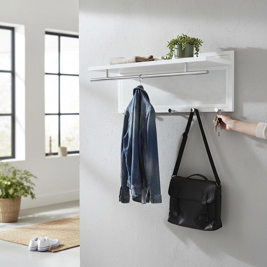 Weiße Wandgarderobe aus Stahlrohr mit Garderobenstange, Haken für Jacken, Handtuchfach und kleinem Regal, beleuchtet durch natürliches Licht in einem modernen Raum.