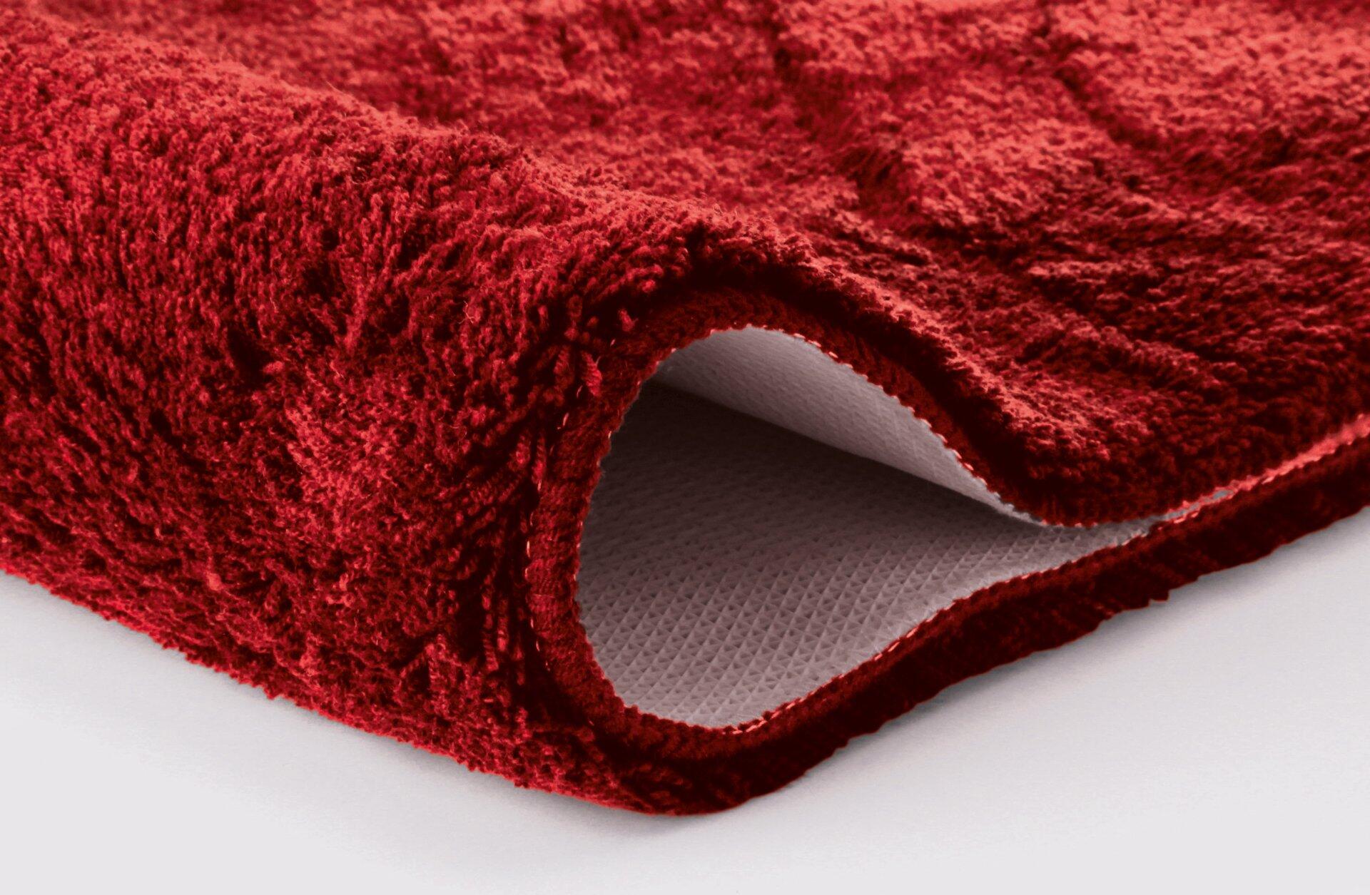 Saturn Badteppich in Granatrot, Detailaufnahme der flauschigen, texturierten Oberfläche und der rutschfesten, wabenförmigen Unterseite.