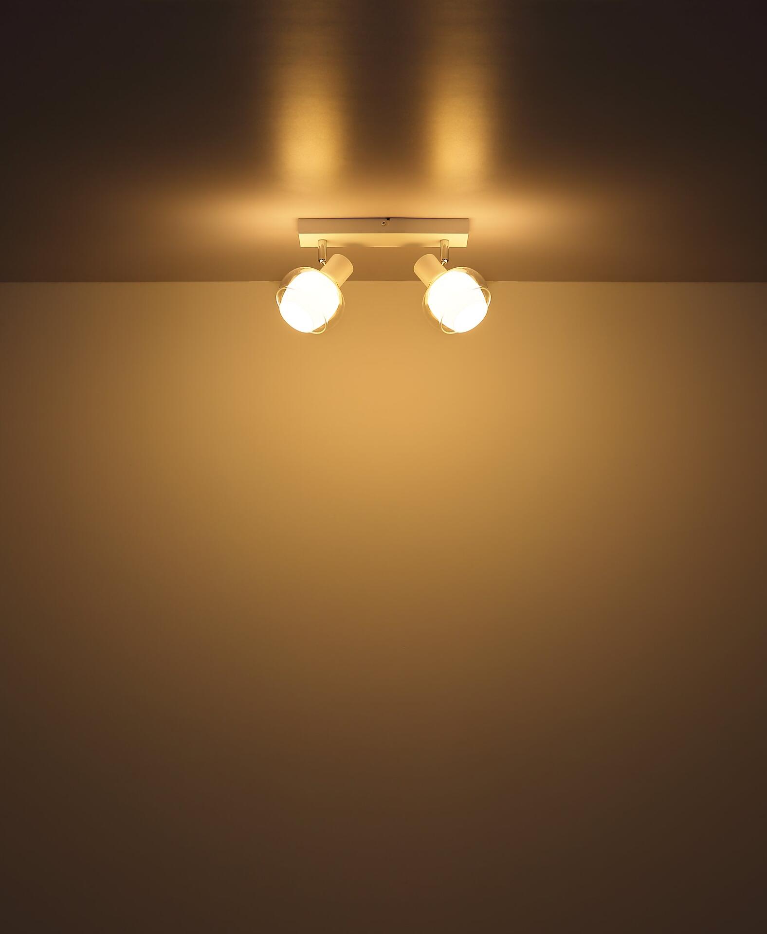 Deckenleuchte TOKKI mit zwei weißen Glaskugeln, frontal aufgenommen und mit hellen Lichtpunkten auf der Decke.