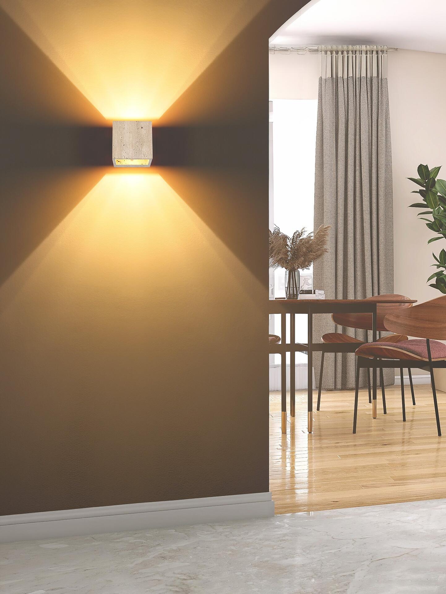 Wandleuchte ROJAS mit Travertin-Glas, die an einer Wand angebracht ist und durch ihr warmes, indirektes Licht eine stimmungsvolle Atmosphäre schafft.