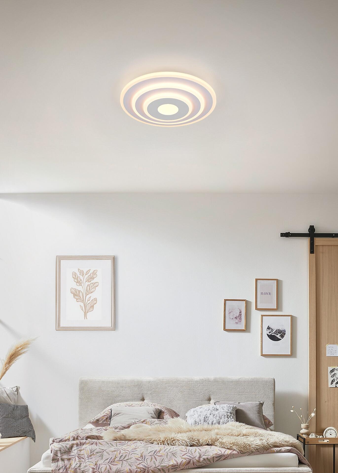 Deckenleuchte Goya im Schlafzimmer, zeigt die runde, flache Leuchte mit konzentrischen Lichtringen und indirekter Beleuchtung.
