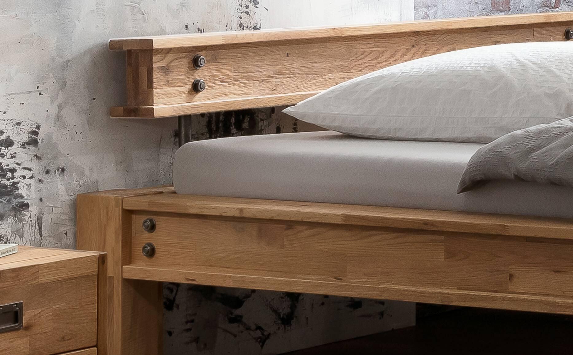 Bettgestell San Sebastian mit hellem Holz, Detailaufnahme des Bettkopfs mit Metallbolzen und Bettkasten.