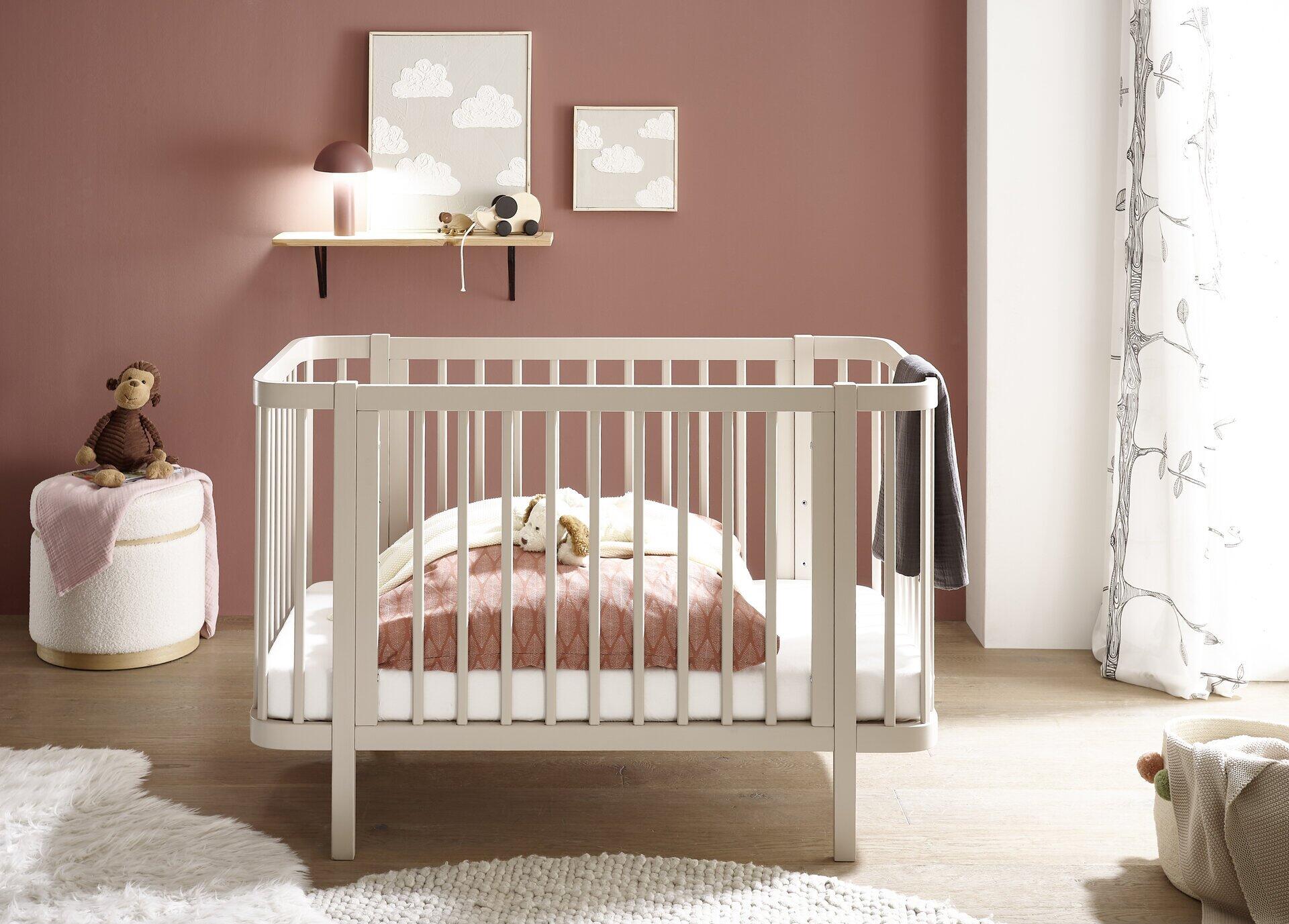 Weißes Babybett Peppini mit Umbauseite, abgerundeten Ecken und hohen Lehnen für erhöhte Sicherheit, im hellen Babyzimmereinrichtung.