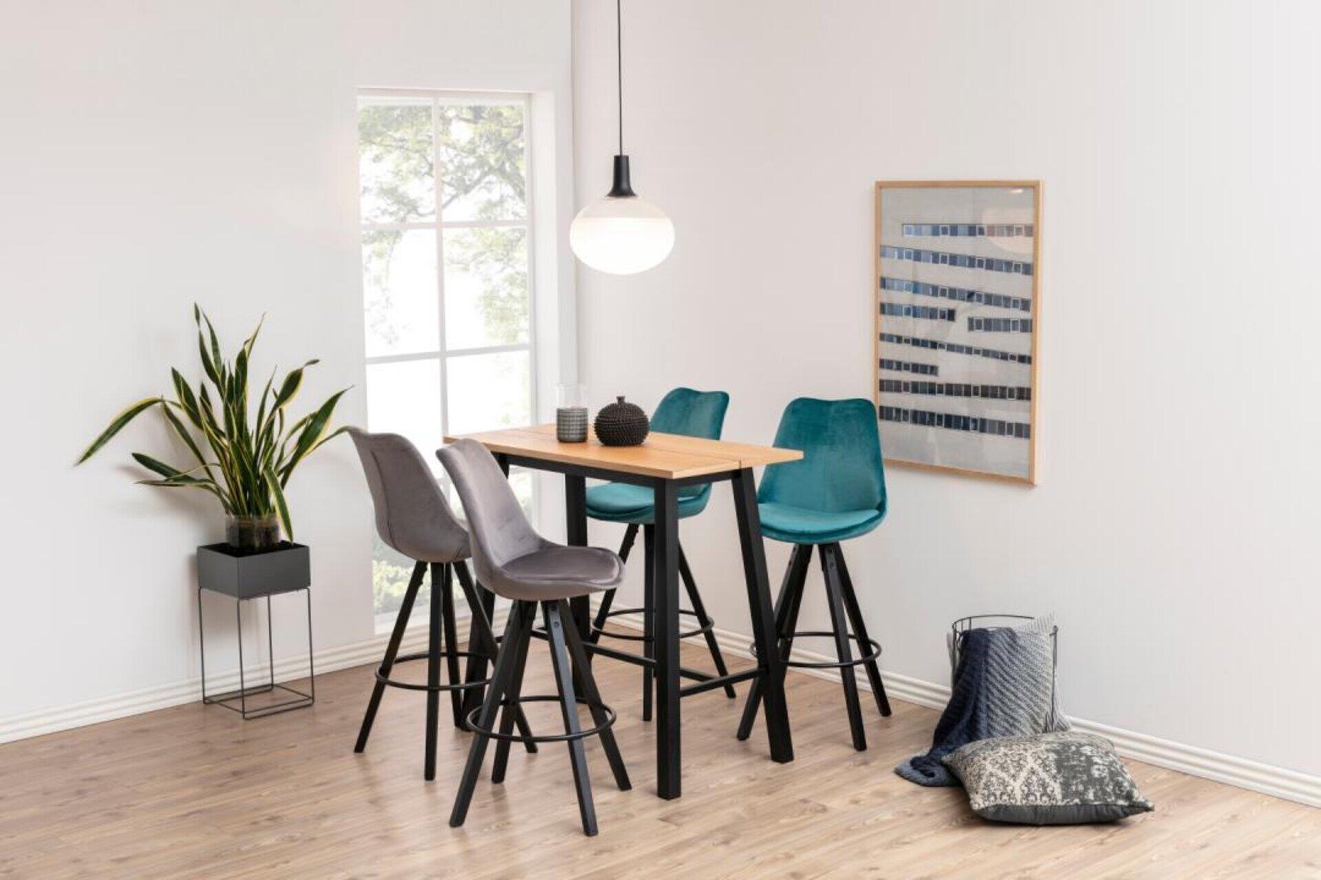 Bartisch Chara mit Splittop-Optik und Naturholzplatte, umgeben von drei Barhocker in Grau und Türkisblau, dargestellt in einem modernen Essbereich.