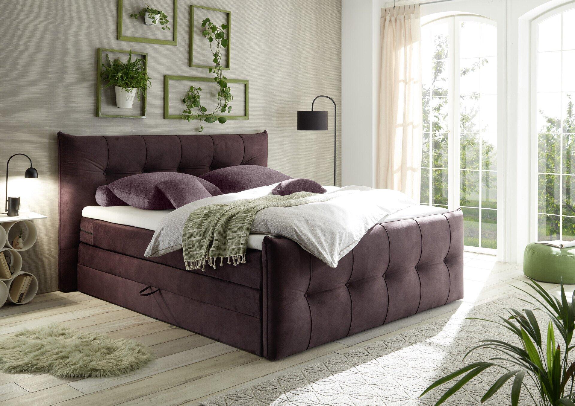 Boxspringbett Maracana 6 mit tiefviolettem Samtbezug, hochgestelltem Kopfteil mit diamantförmiger Polsterung und integrierten Schubladen für Stauraum.