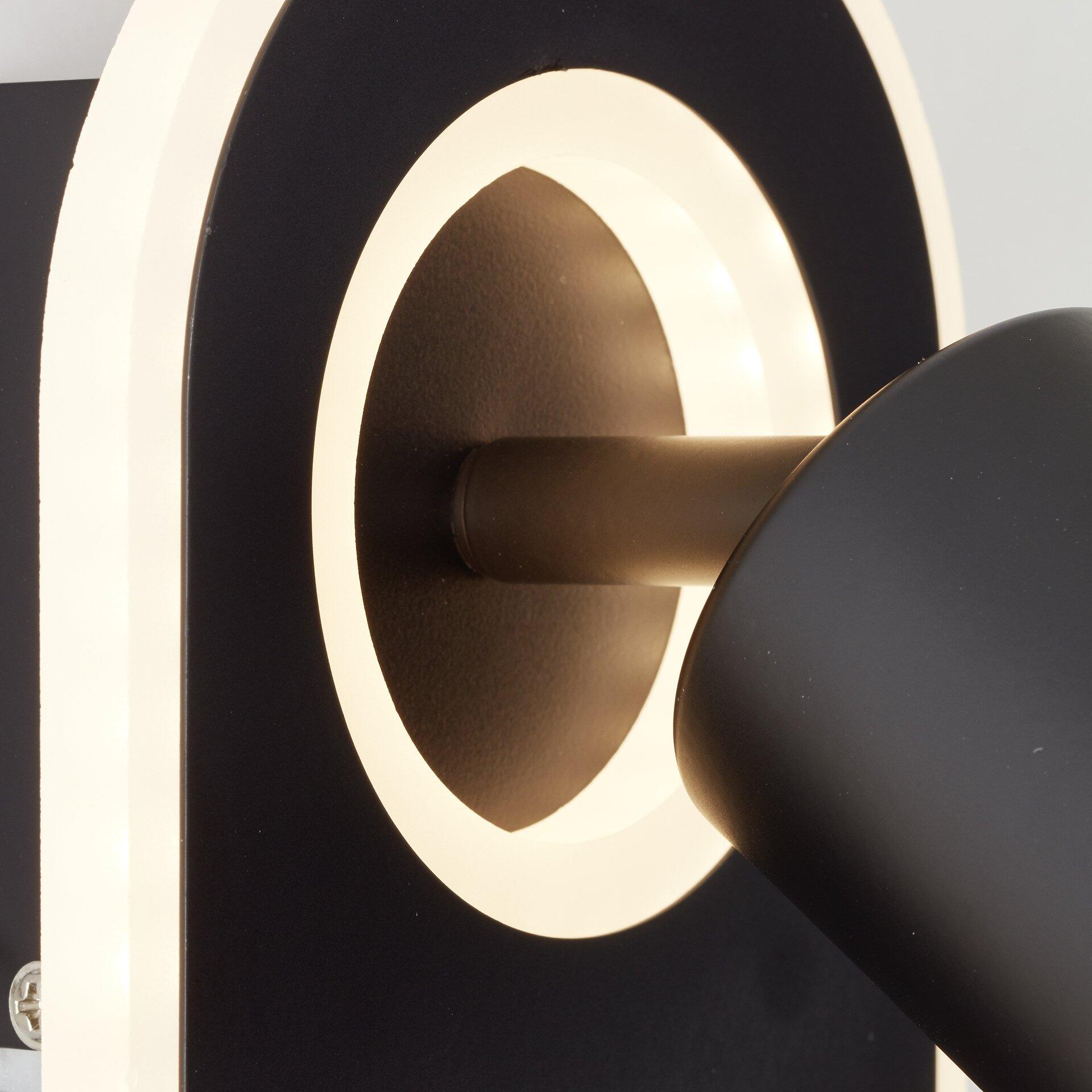 Spotleuchte Kimon mit schwenkbarem Lampenkopf und minimalistischem Design, Detailaufnahme des schwarzen Lampenkopfs und weißen Rahmens vor schwarzem Hintergrund.