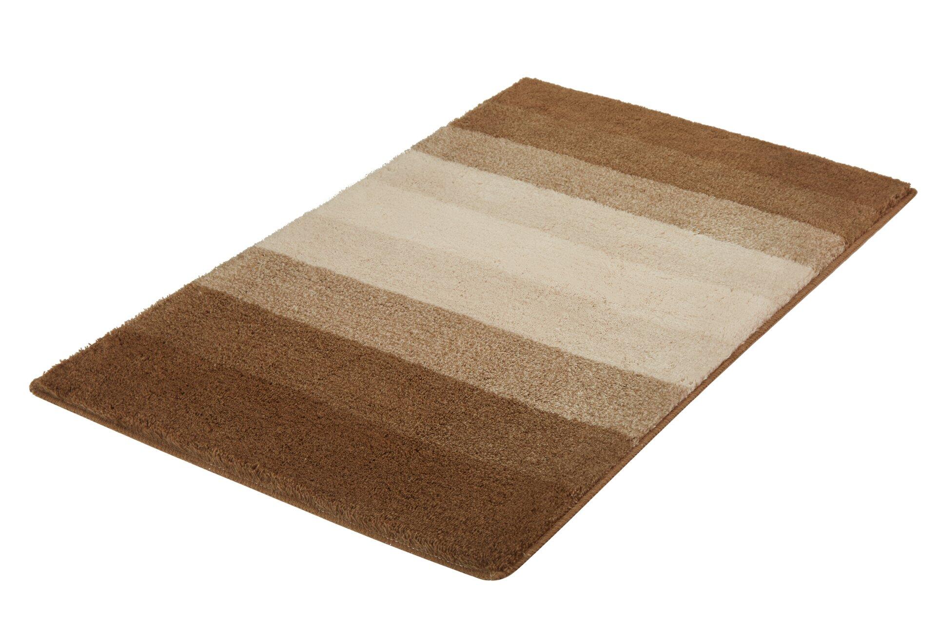 Badteppich Palace mit gestreiftem Design in Beige- und Brauntönen, zeigt die flauschige Textur in einer schrägen Studioaufnahme.