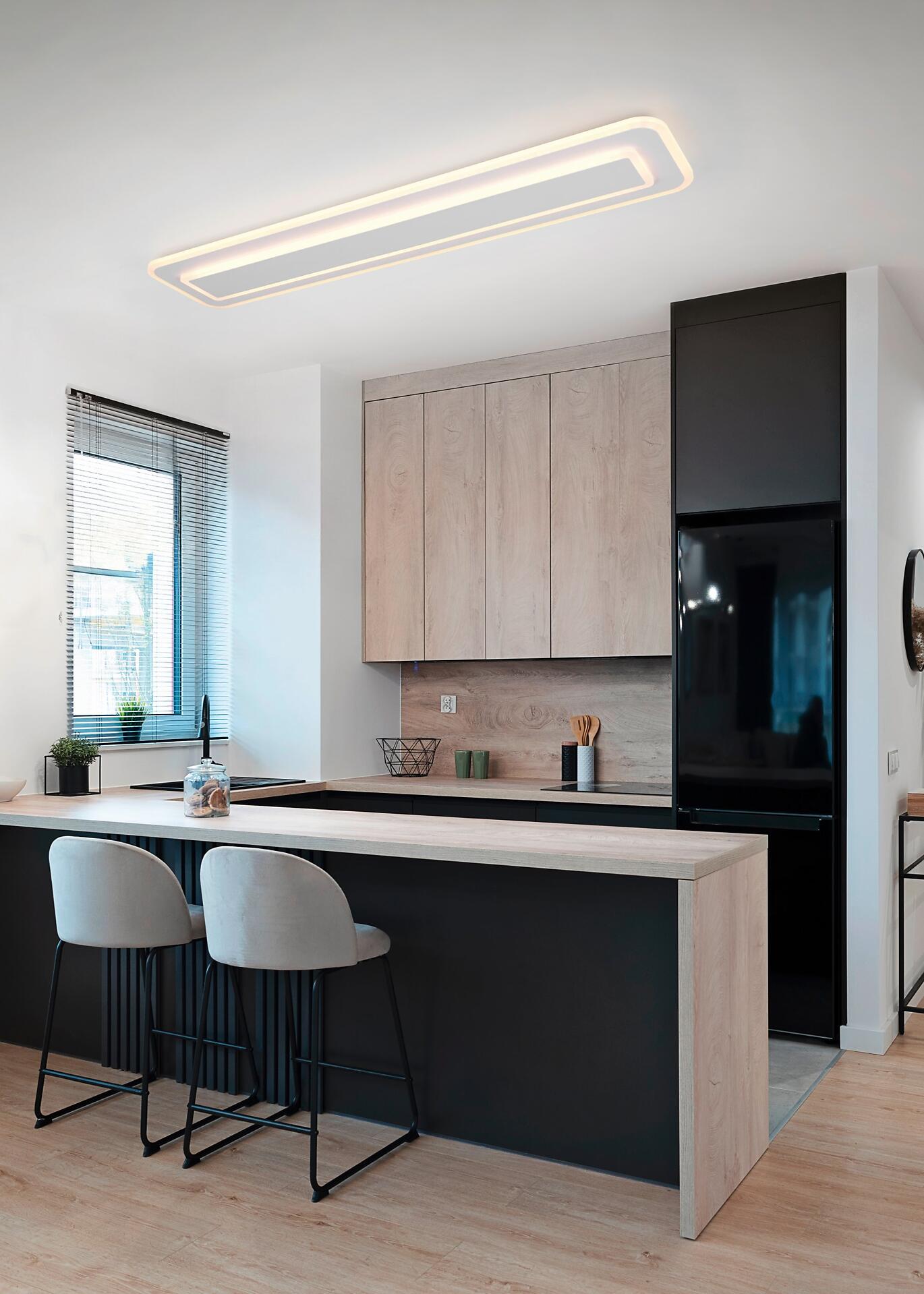Deckenleuchte Riva mit integrierter LED-Beleuchtung über einer modernen Kücheninsel, die ein warmes Licht auf die Arbeitsfläche und die Umgebung wirft.