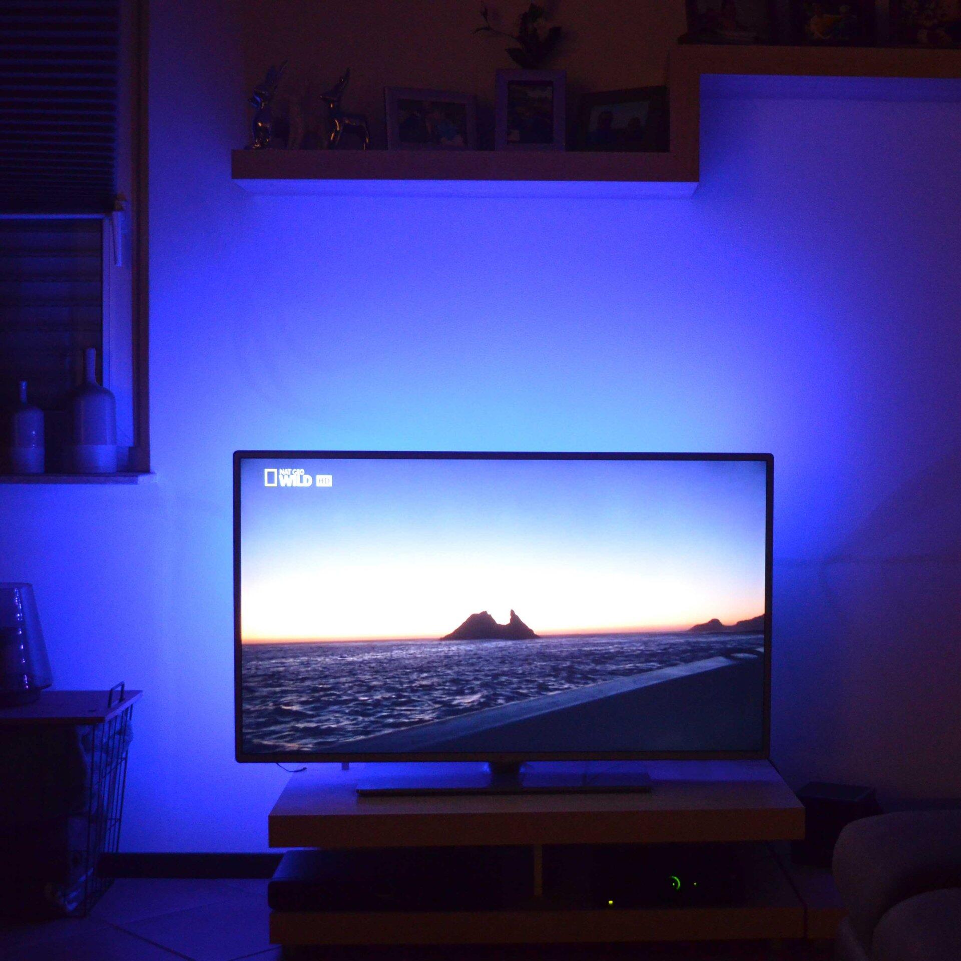 LED Band BRILO beleuchtet den Fernseher in einem modernen Wohnzimmer, das eine entspannte Atmosphäre mit Blick auf den Horizont schafft.