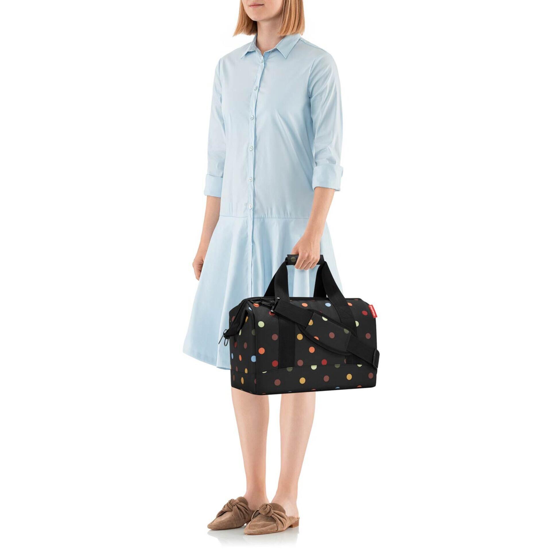 Frau mit schwarzem Reisekoffer mit bunten Details im Allrounder m Stil.
