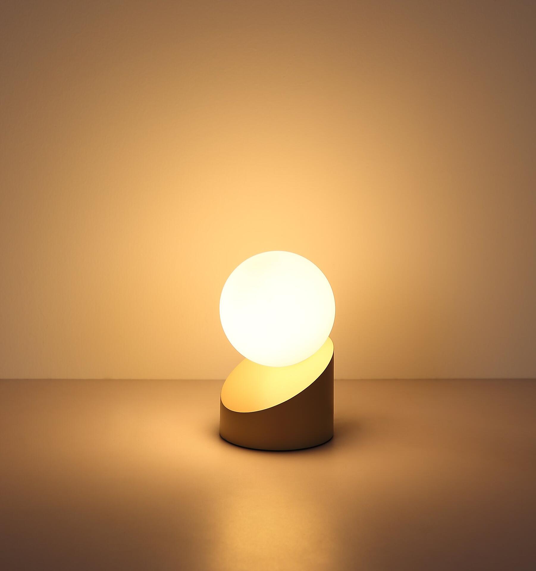 Tischleuchte ALISA mit goldener Basis, halbmondförmiger Struktur und runder Leuchtglas-Kugel, die per Touch-Funktion ein- und ausgeschaltet wird.