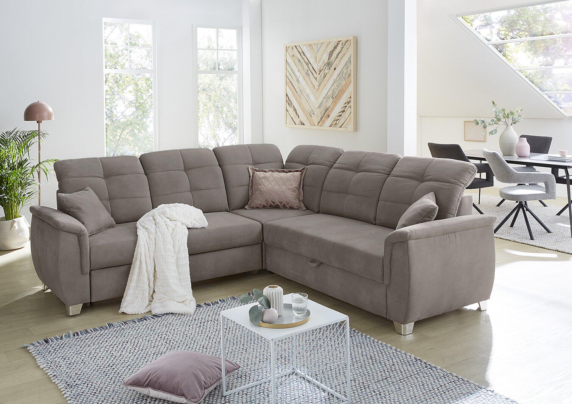 Moderne Wohnlandschaft Udine mit grau-rosa Kissen, verstellbaren Kopfstützen und Relaxfunktion, leicht erhöhte Frontperspektive.