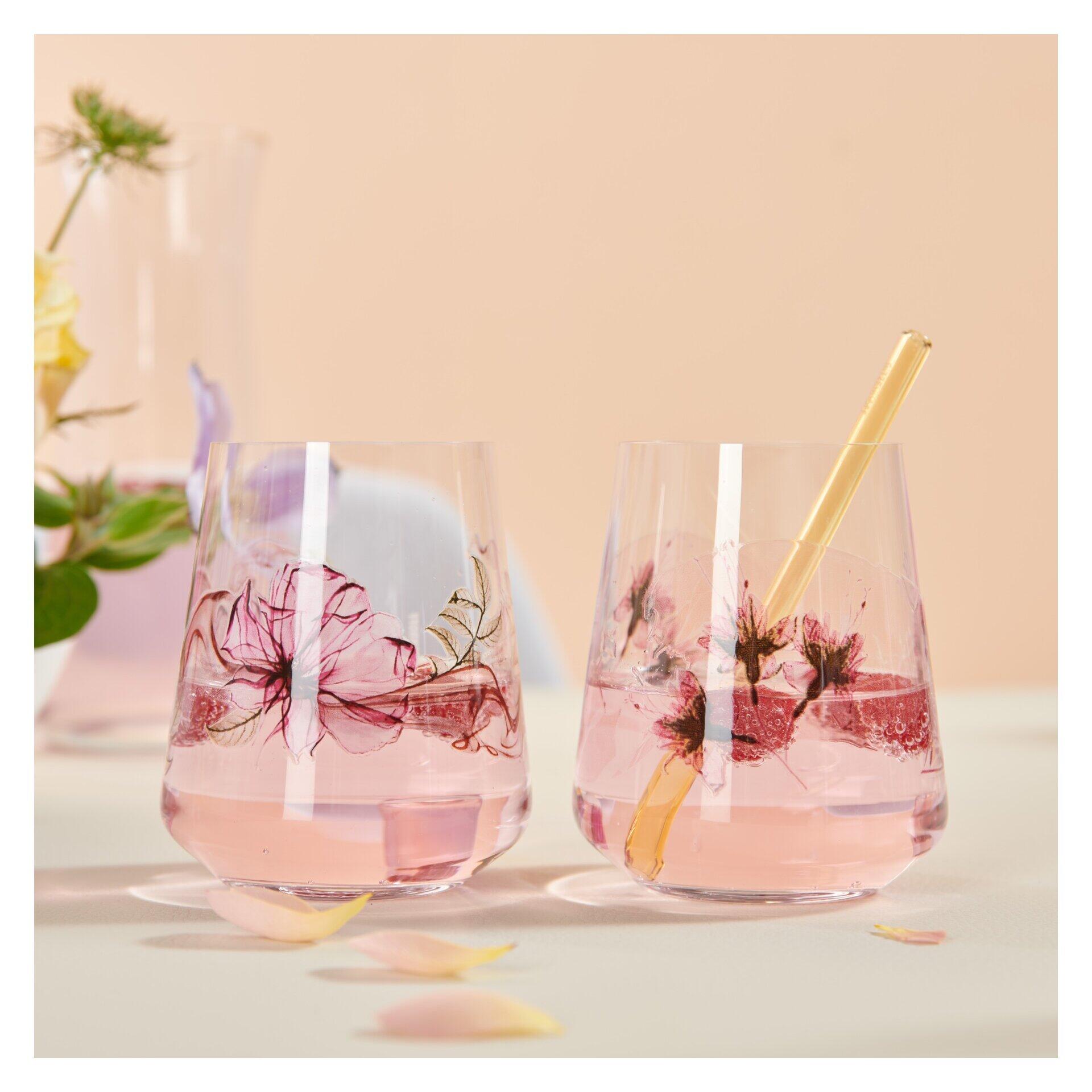 Zwei Aperitif-Gläser aus dem Universalglas-Set mit rosafarbenem Getränk, Blüten und goldenem Strohhalm, aus der Vogelperspektive betrachtet.