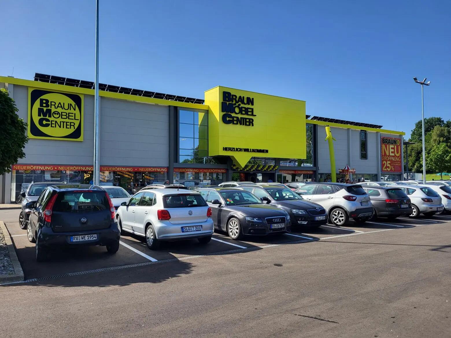 Braun Möbel Center Neueröffnung mit 25% Rabatt, Parkplatz mit mehreren Autos und Willkommensschild.