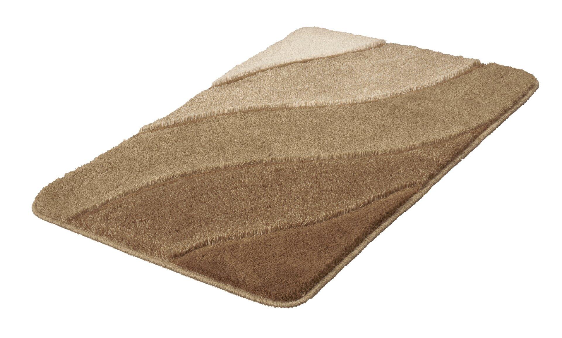Badteppich Serenade in Taupe mit gewellten, dynamischen Streifen und abgerundeten Ecken, aus der Vogelperspektive leicht zur Seite dargestellt.