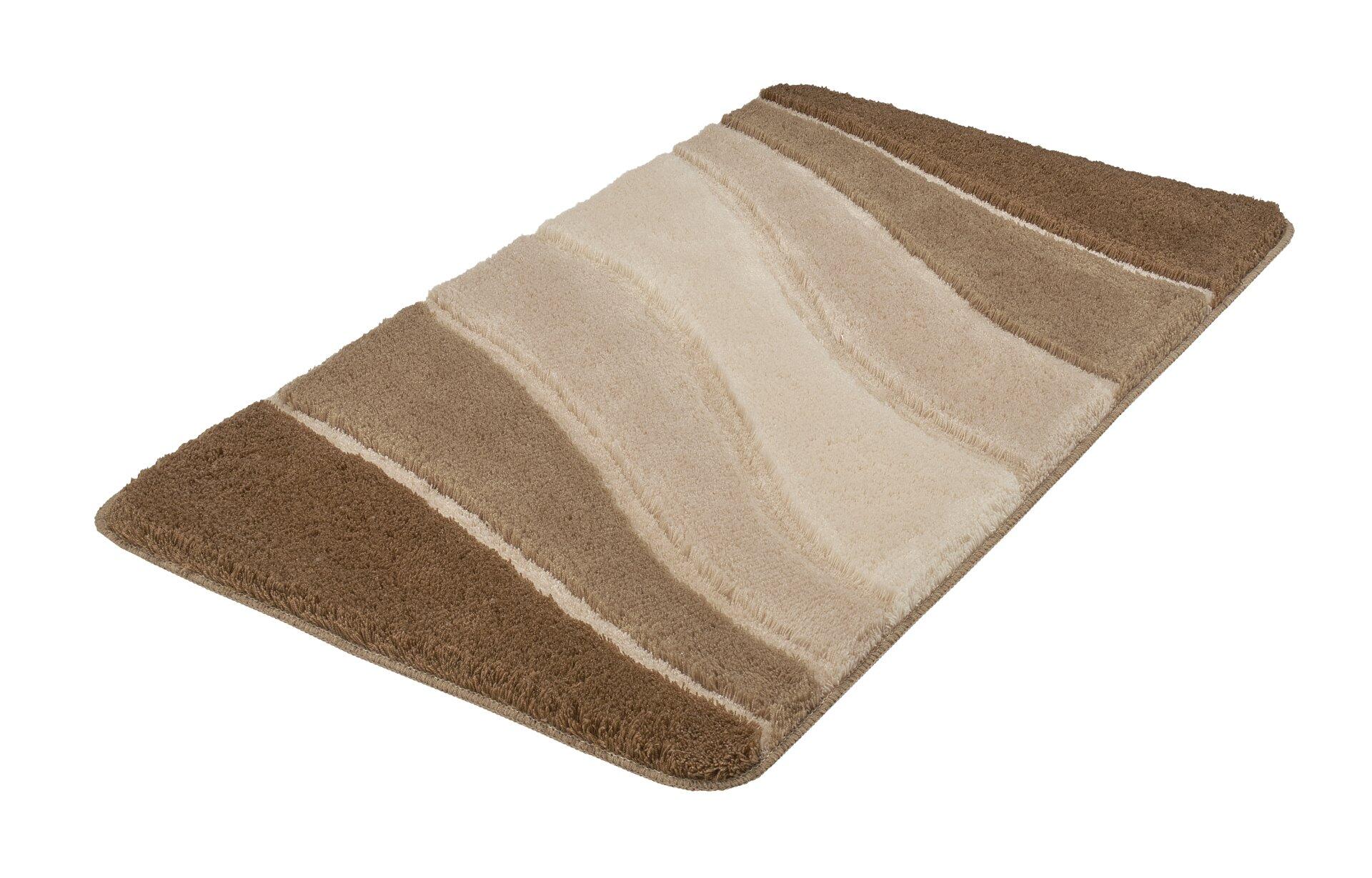 Flauschiger Badteppich Ocean mit horizontalen, gewellten Streifen in Beige, Hellbraun und Dunkelbraun auf weißem Hintergrund.