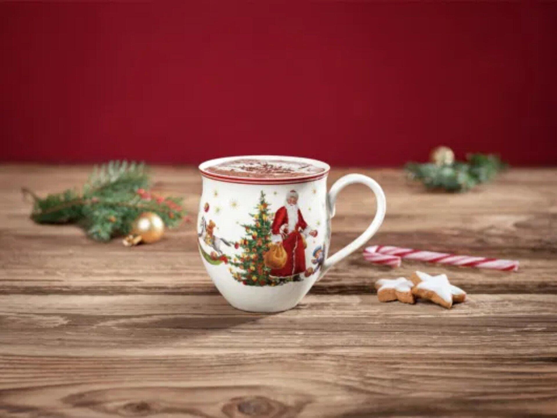 Weihnachtsmug von Toy's Delight mit festlicher Szene von Santa Claus, Elfen und Weihnachtsschmuck, dargestellt auf einer rustikalen Holzplatte mit Tannengrün und Lebkuchen.