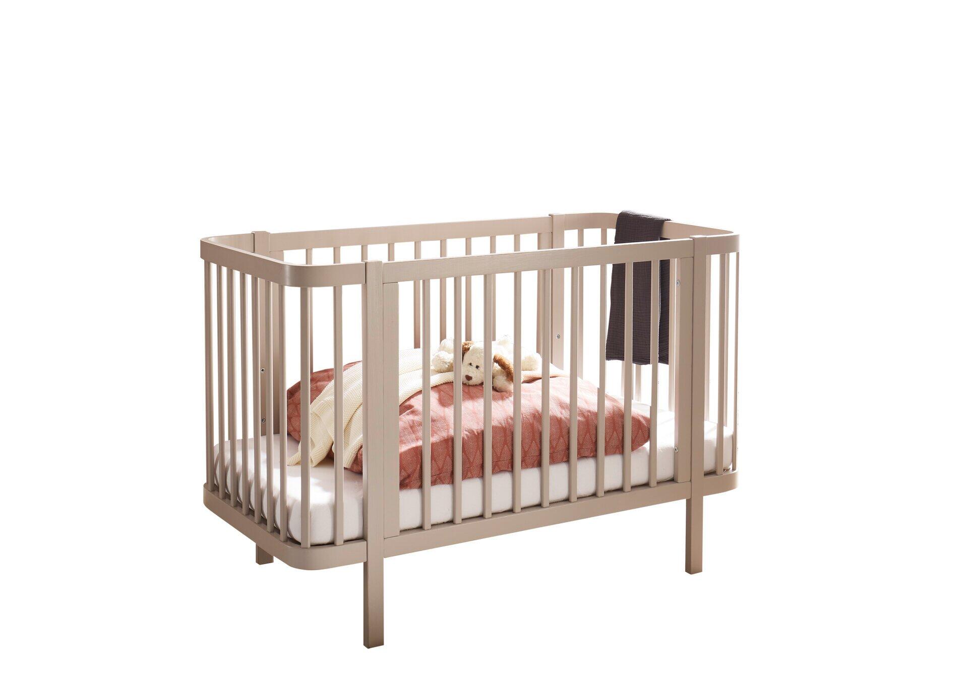 Babybett Peppini mit Umbauseite und abgerundeten Ecken, dargestellt in Frontalperspektive mit Fokus auf die vertikalen Holzleisten der Seitenteile und den langen, schmalen Füßen.
