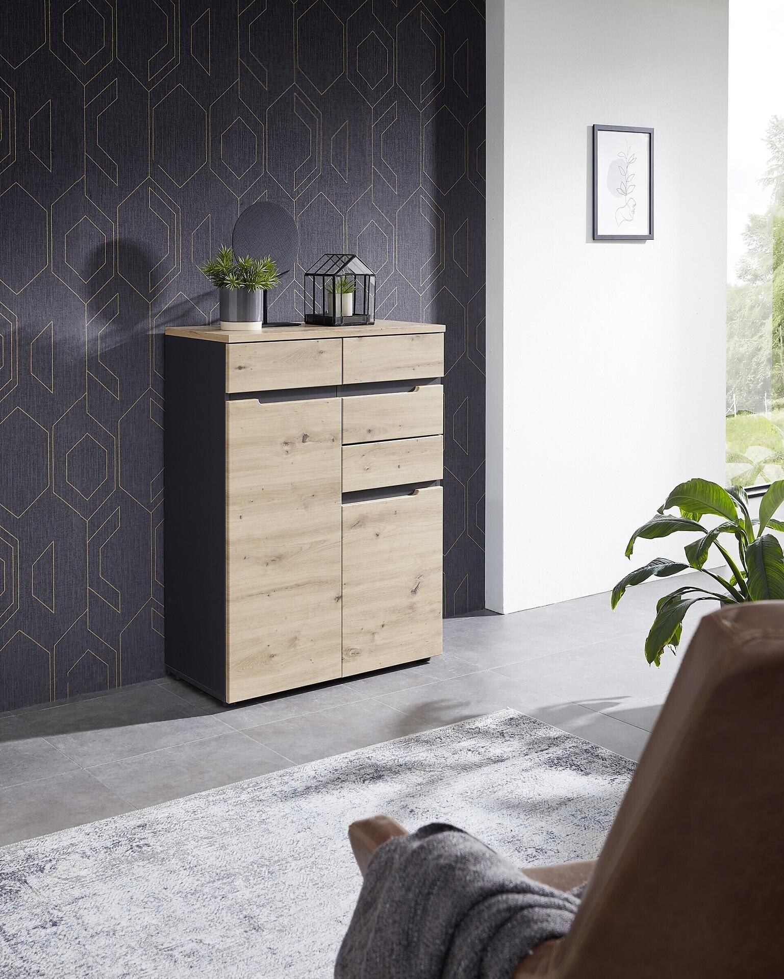 Detroit Kommode aus Artisan Eiche mit drei Schubladen und einer Tür, leicht seitlich dargestellt, um die Tiefe und Kombination aus hellen Holzelementen und grauen Flächen zu zeigen.