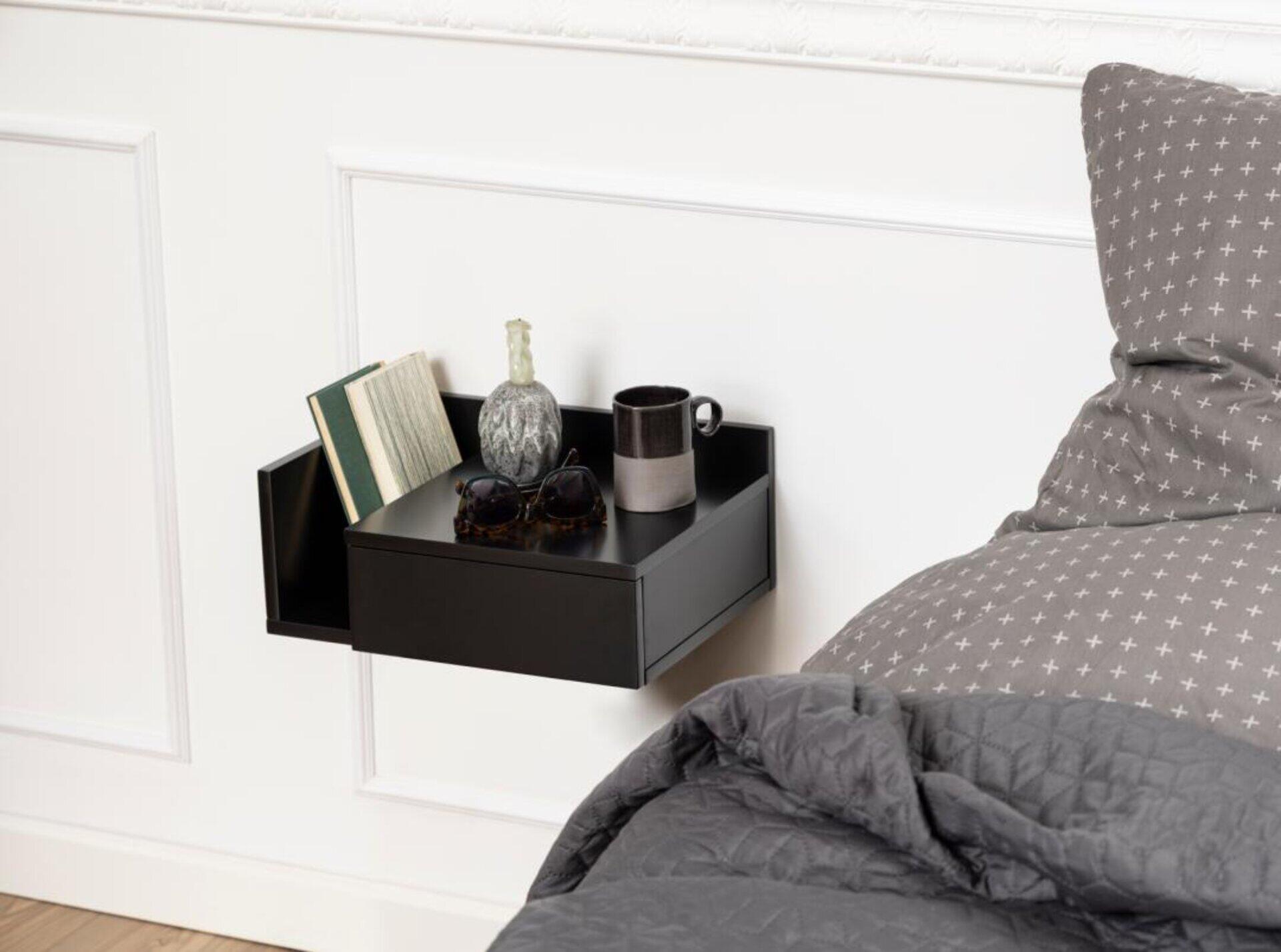 Nachttisch Ashlan in Schwarz, montiert an der Wand mit einer seitlichen Ablagefläche und Platz für Buch, Tasse, Skulptur und Sonnenbrillen.
