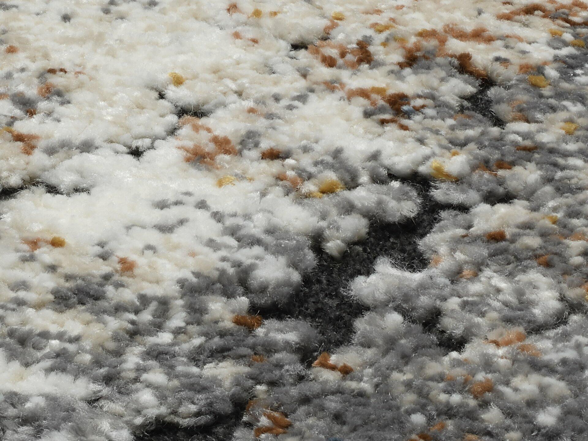 Detailaufnahme des Maschinenwebteppichs Tarsus mit weicher, flaumiger Textur aus hellgrauen, dunkelgrauen und hellbraunen Fäden.