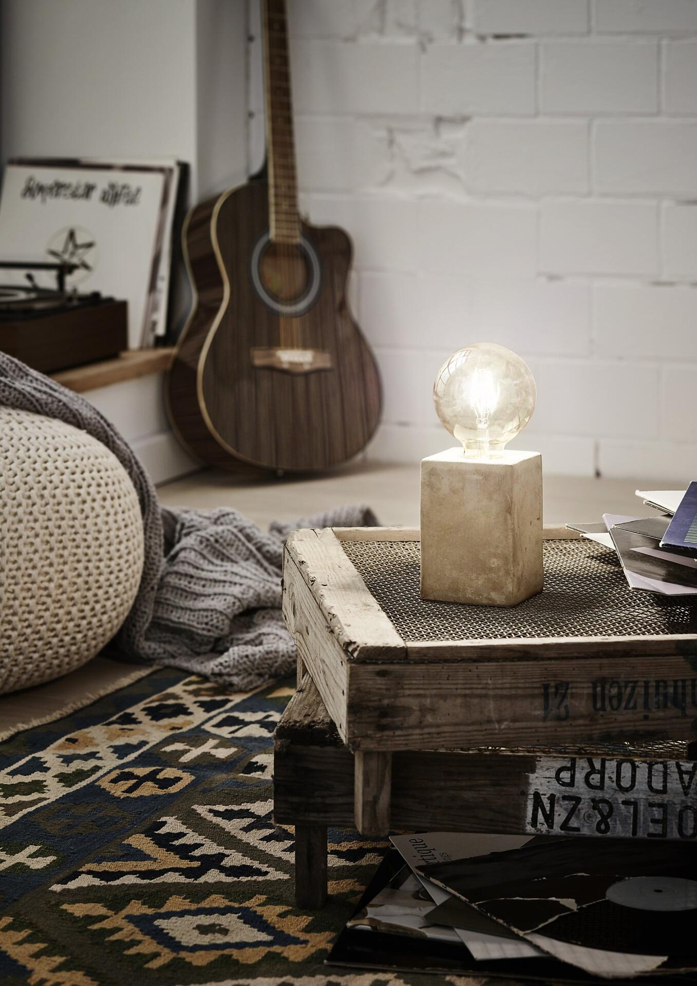 Tischleuchte Prestwick im Vintage-Design mit gläserner Leuchtfläche auf einem rustikalen Holzkasten in einem stilvollen Wohnzimmer.