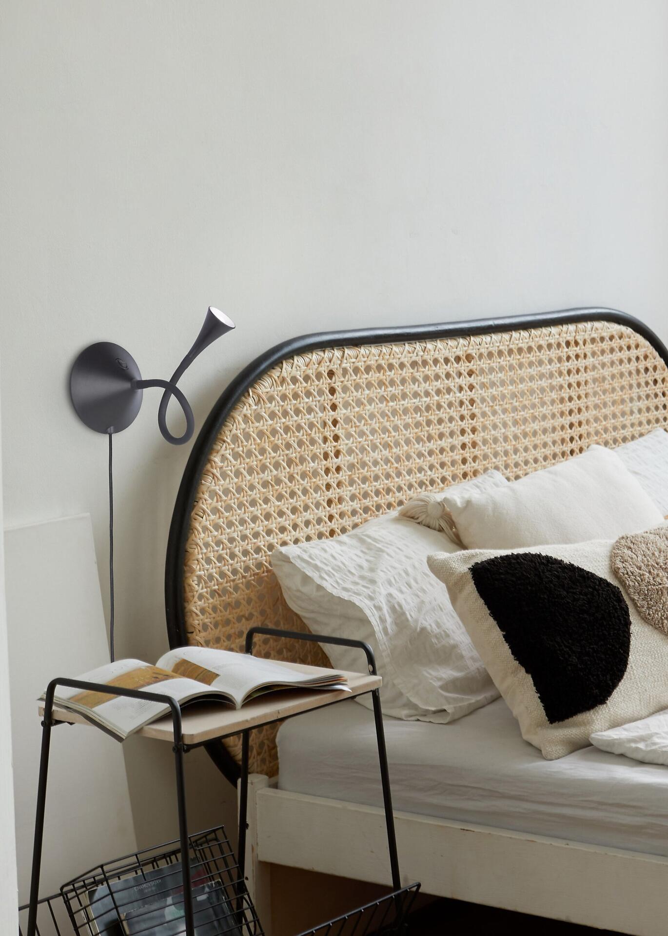 Wandlampe Viper mit beweglicher Armatur, befestigt an der Wand neben einem Bett mit Korbkopf.