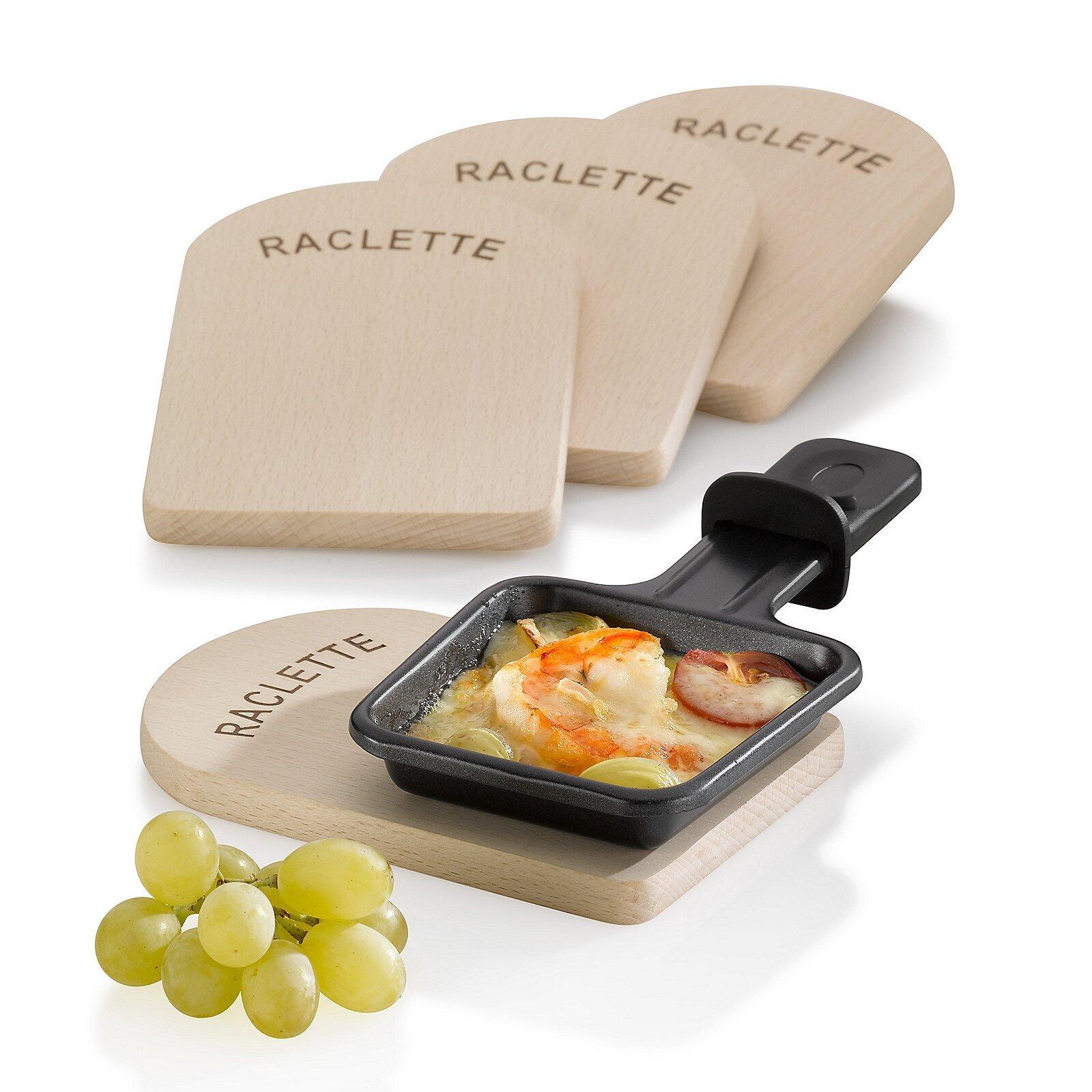 Raclette-Brettchen Baar mit schwarzer Metall-Raclette-Pfanne, gefüllt mit geschmolzenem Käse, Kartoffelscheiben, Paprika und Gewürzgurken, präsentiert auf einem Holzbrett mit "Raclette"-Aufschrift.