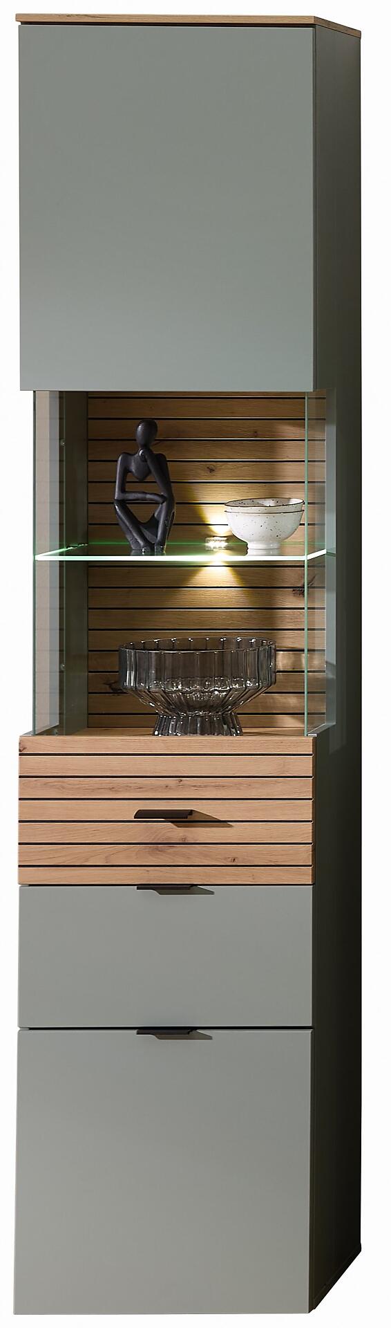 Vitrine Ina mit Artisan Eiche Akzenten und Schilfgrau-Front, zeigt eine Frontalansicht mit geschlossener Schublade, Glastür und offenen Regalen inklusive LED-Beleuchtung.
