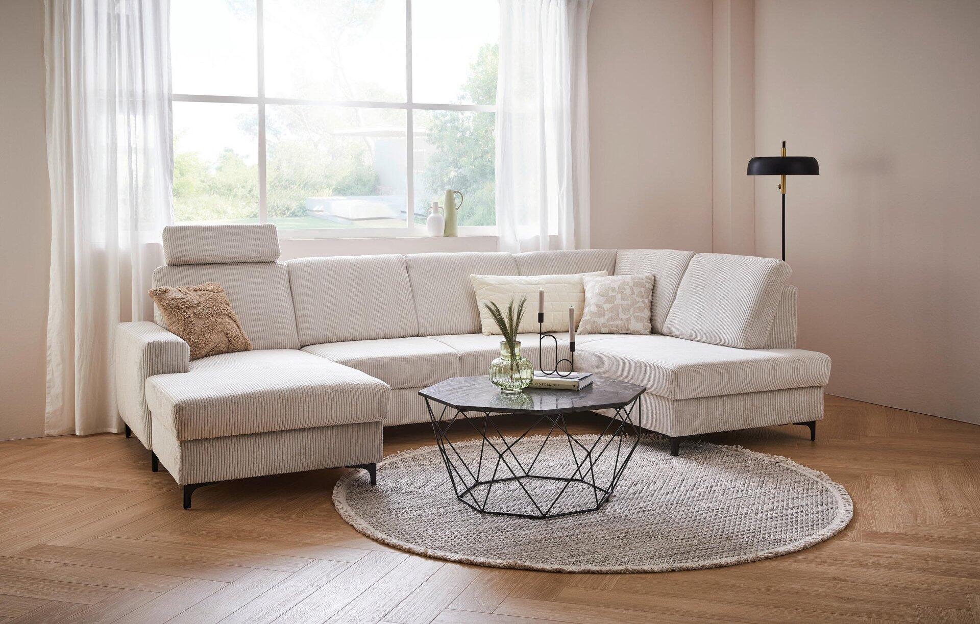 Wohnlandschaft Balina mit L-Form, verstellbarer Rückenlehne und Winkelfüßen in Schwarz, dargestellt in einer erhöhten Frontalperspektive im hellen Wohnzimmer.